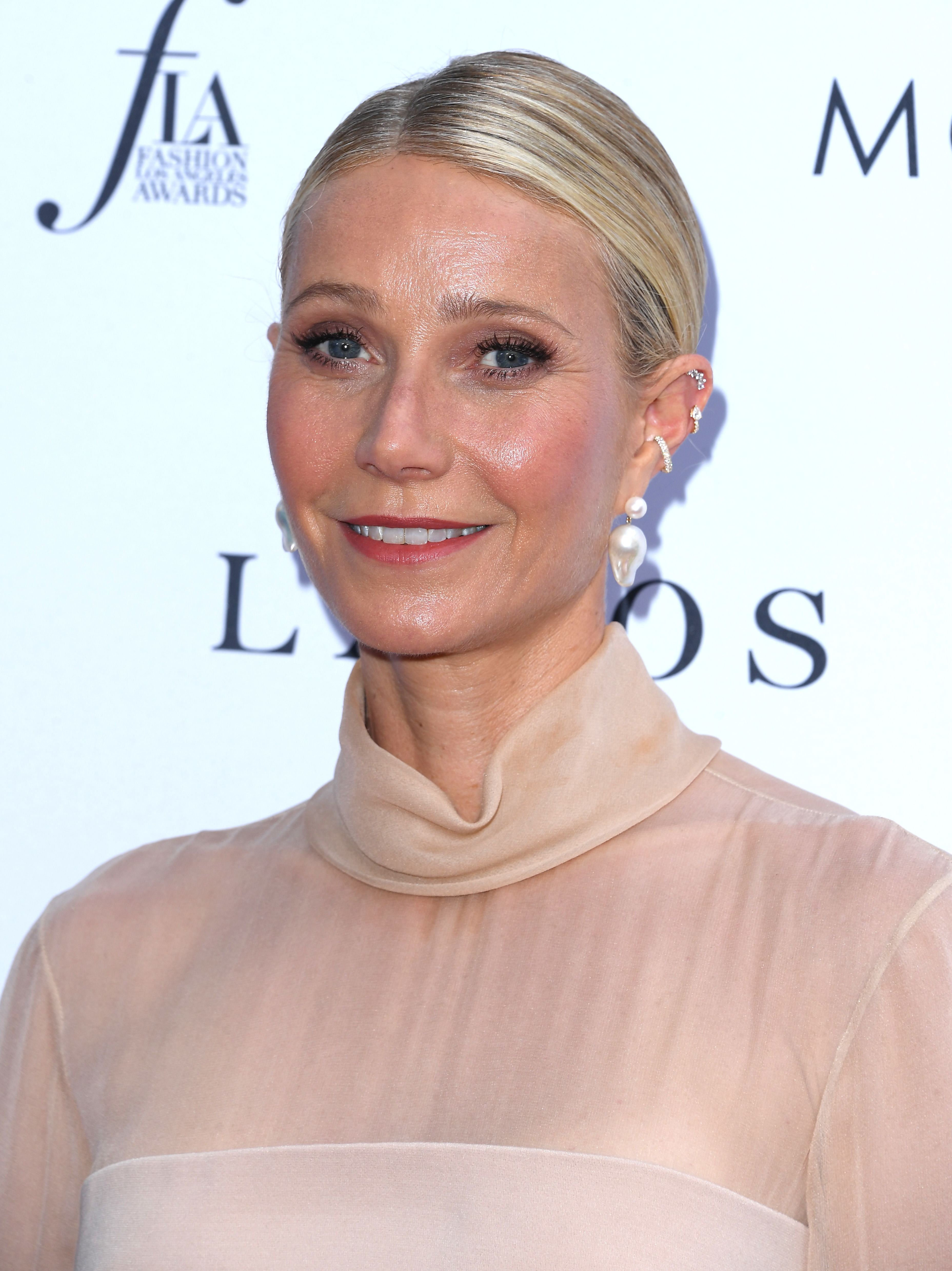 Close-up of Gwyneth smiling at a media event in a diaphanous turtleneck
