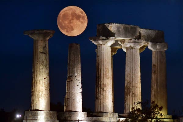 The blue supermoon is seen behind the Apollo Temple in ancient Corinth, Greece