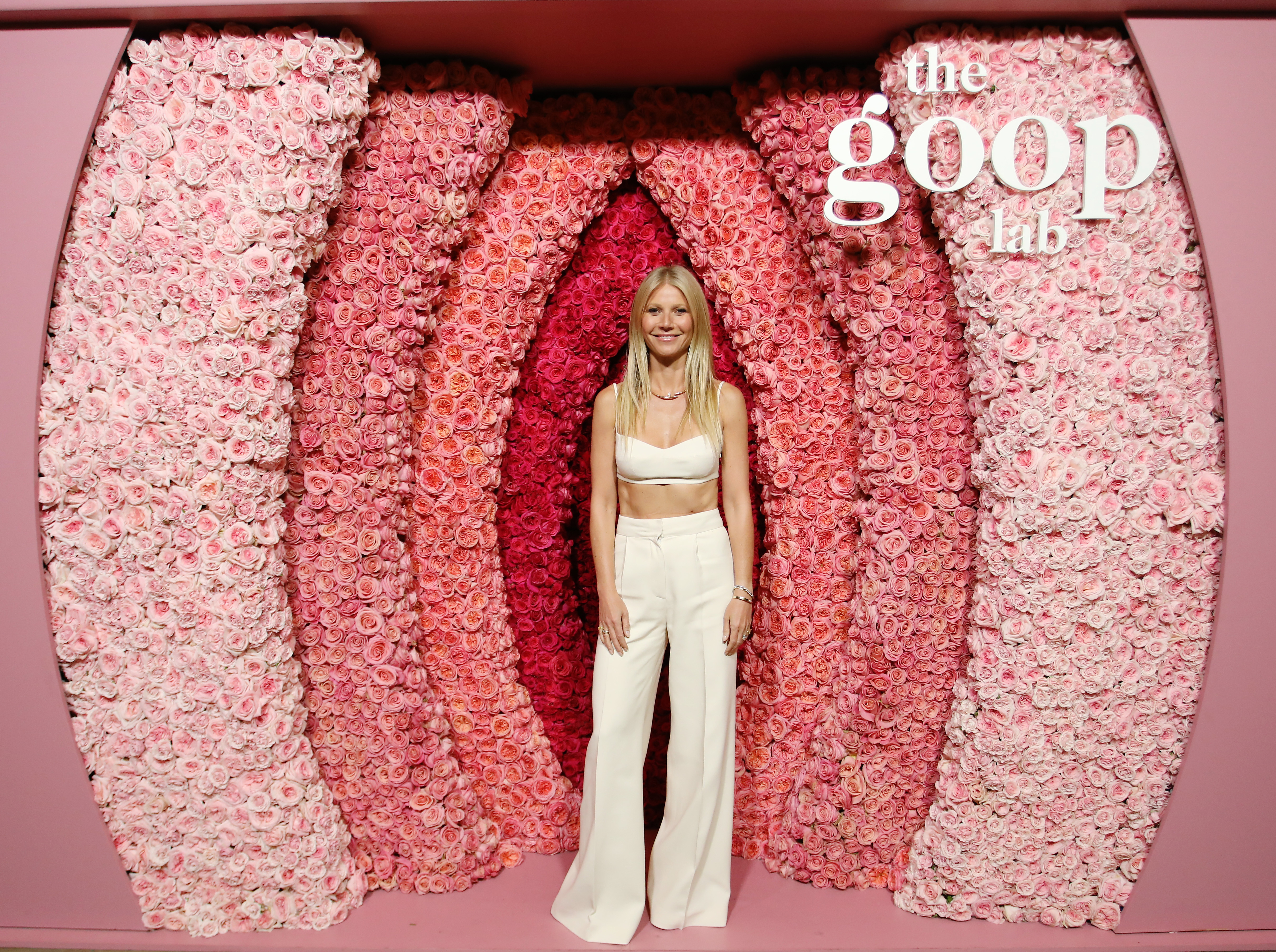 Gwyneth standing in front of &quot;the Goop Lab&quot; vagina-themed design