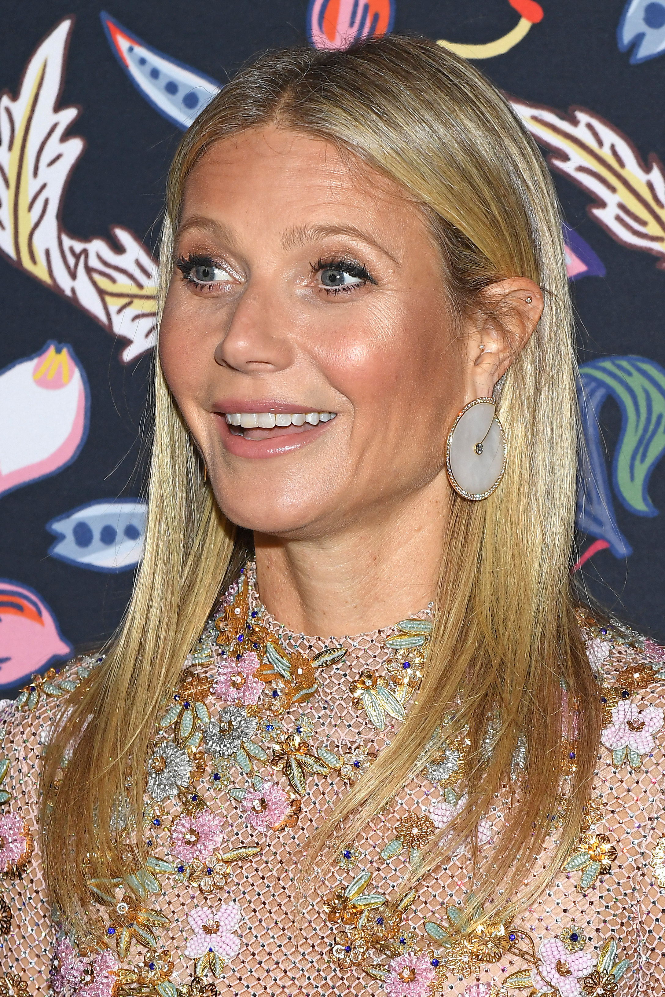 Close-up of Gwyneth at a media event wearing a colorful mesh outfit