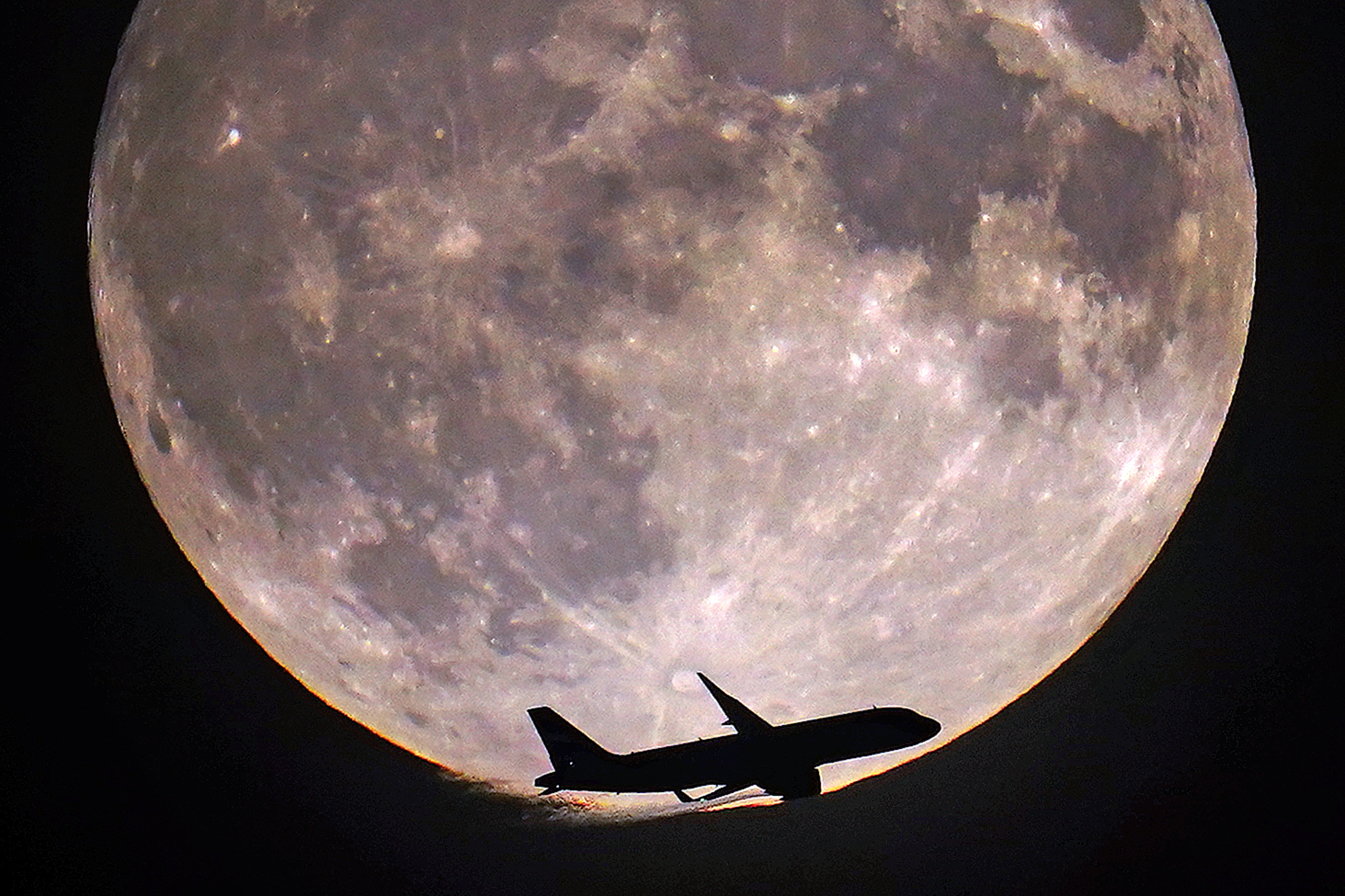A plane flying in front of the moon