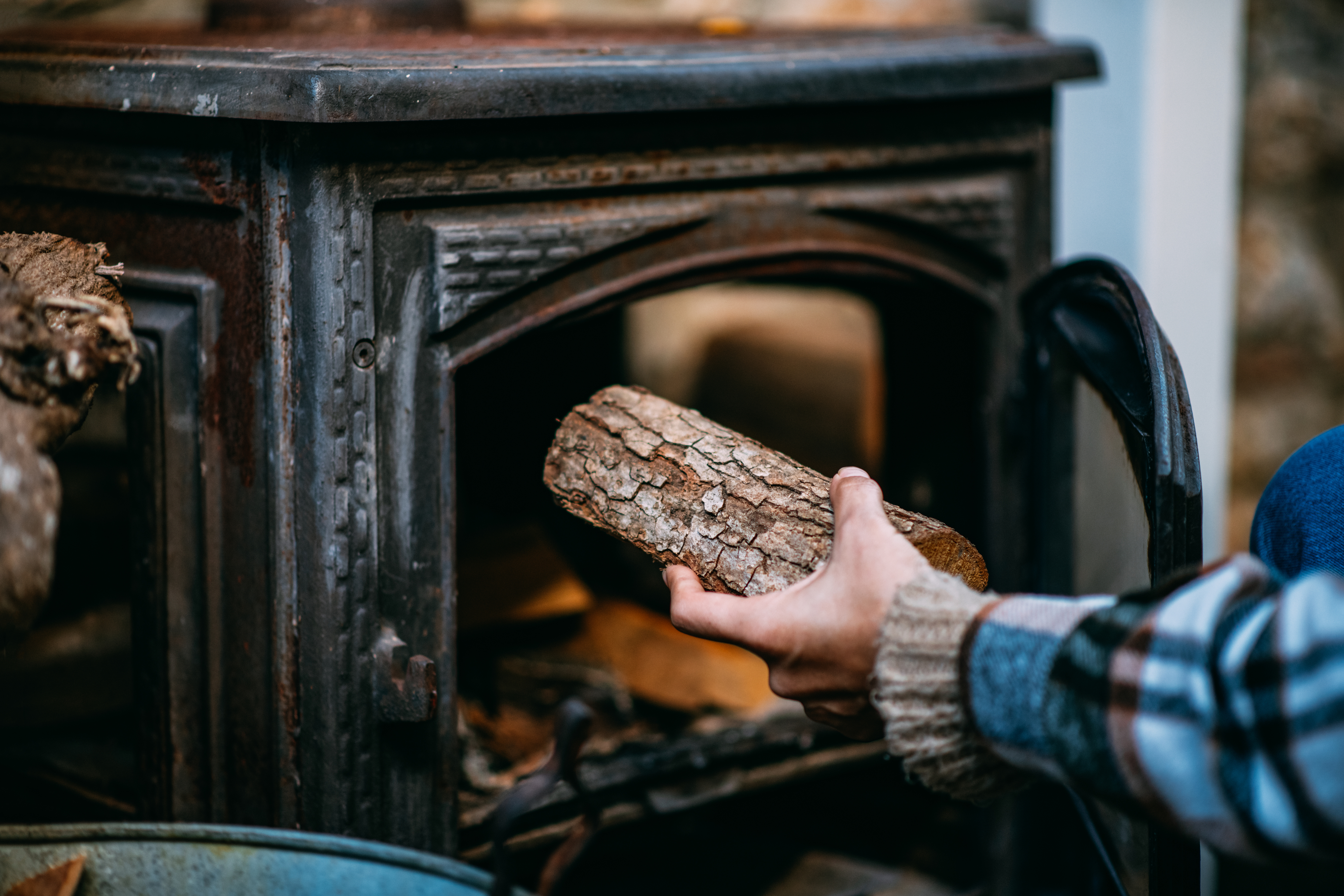 person putting a log in a wood burning stove