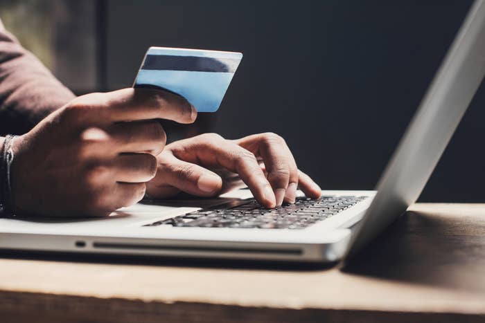 person with their credit card at their laptop