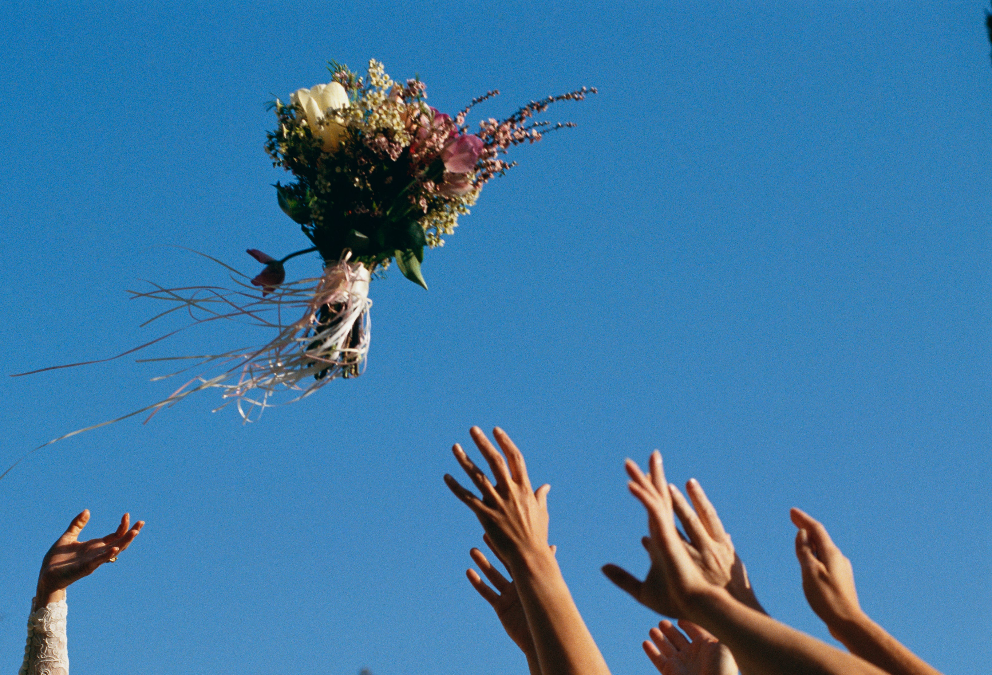Hands reaching for wedding bouquet