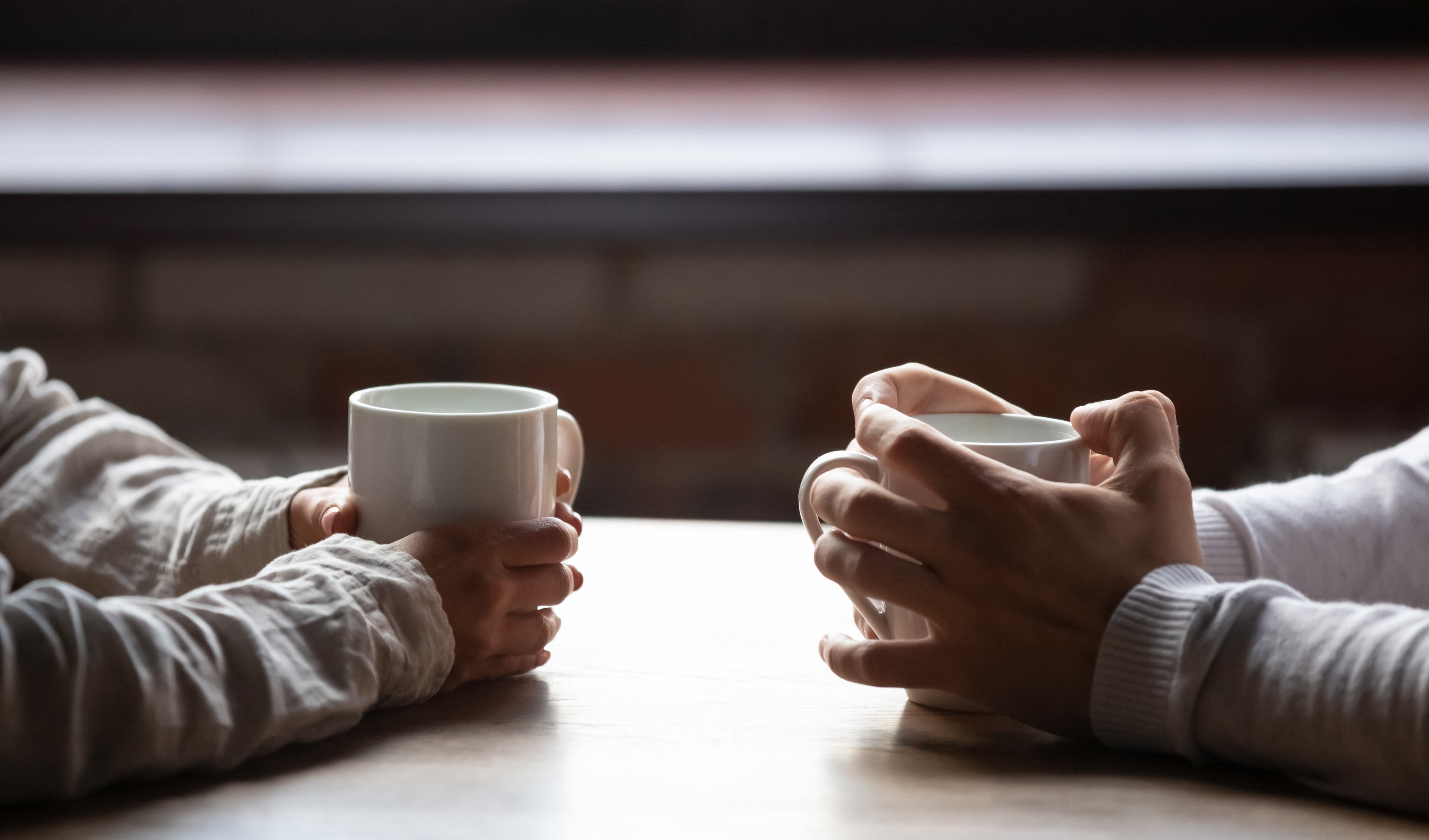 Two people holding mugs across from each other