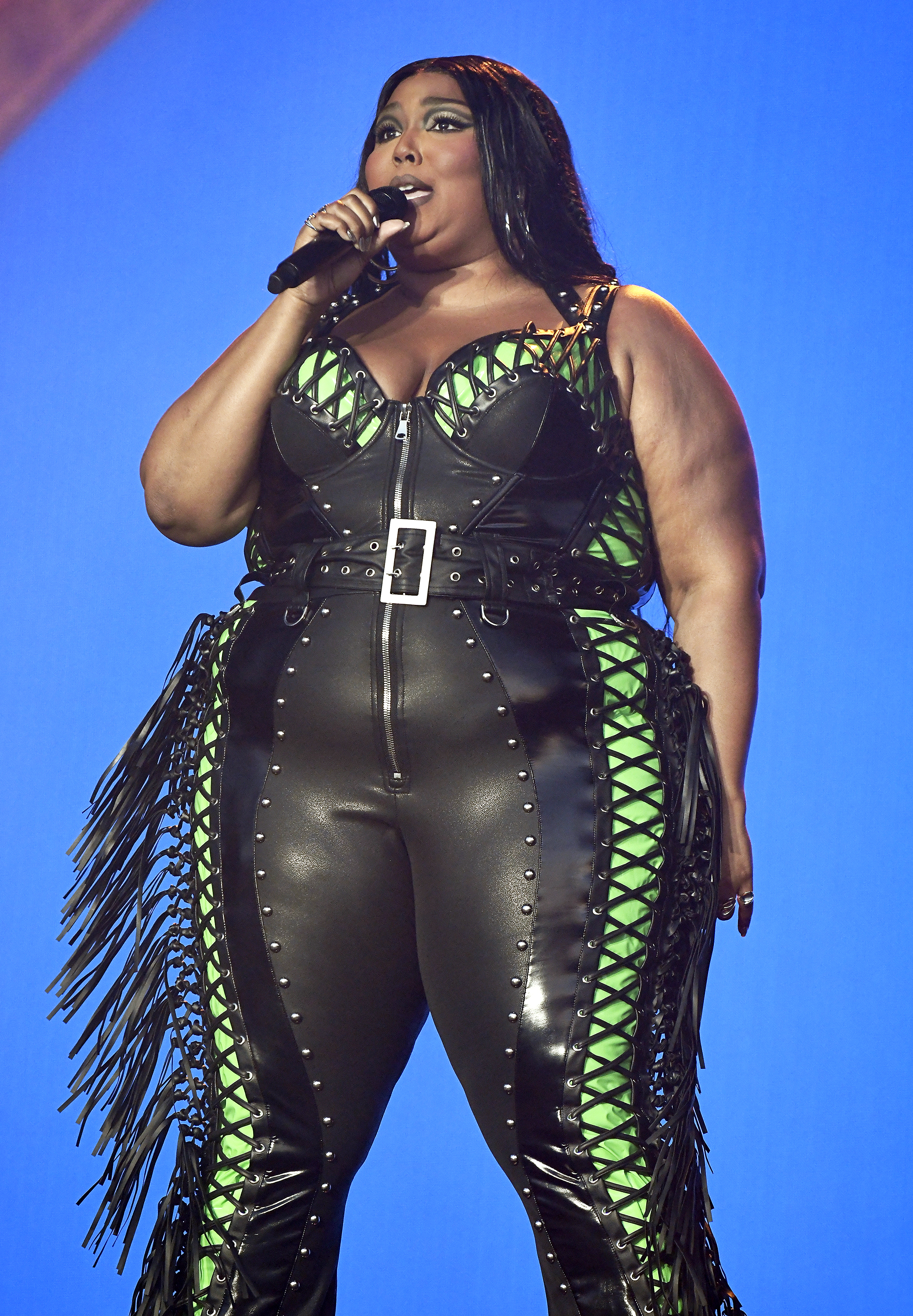 Close-up of Lizzo performing in a belted leather jumpsuit
