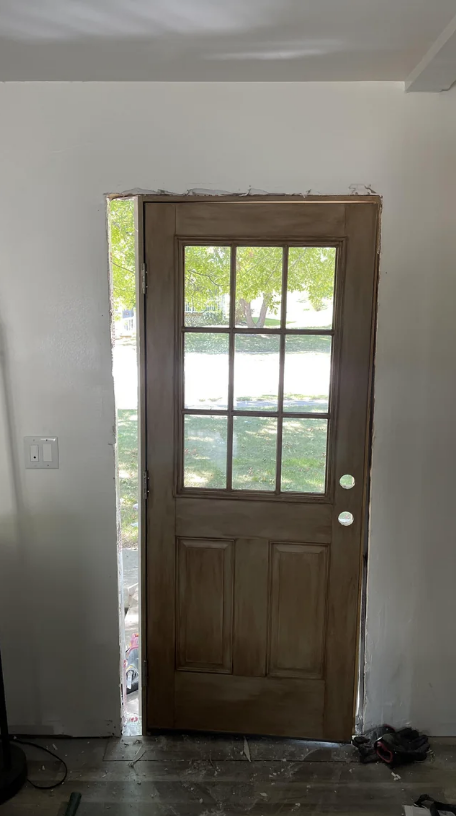 A wooden door that&#x27;s standing in a doorway that&#x27;s too big for it