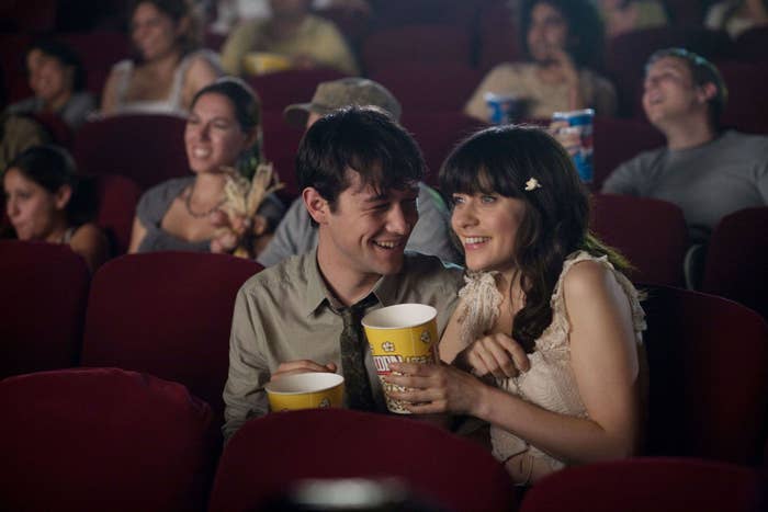 A couple eating popcorn and watching a movie in a theater