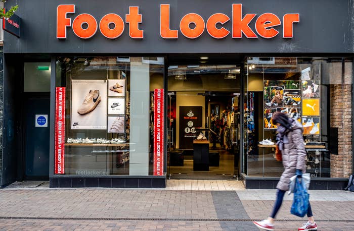Foot Locker High Street Retail Chain Shop Front With Woman Walking Past Carrying Shopping Bag