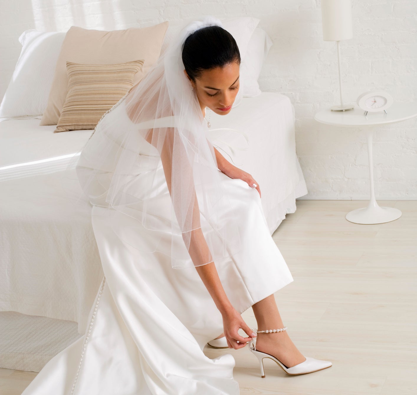 bride in her dress putting her heels on