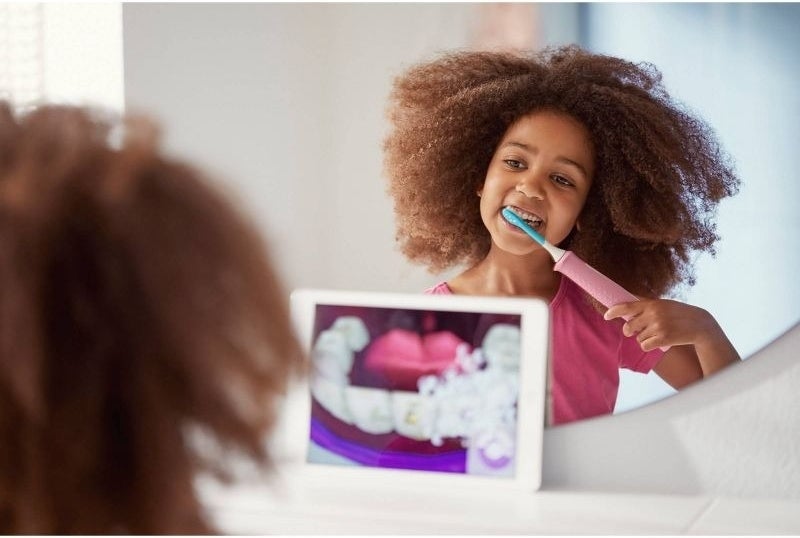 Child brushes teeth while looking at an app on a tablet