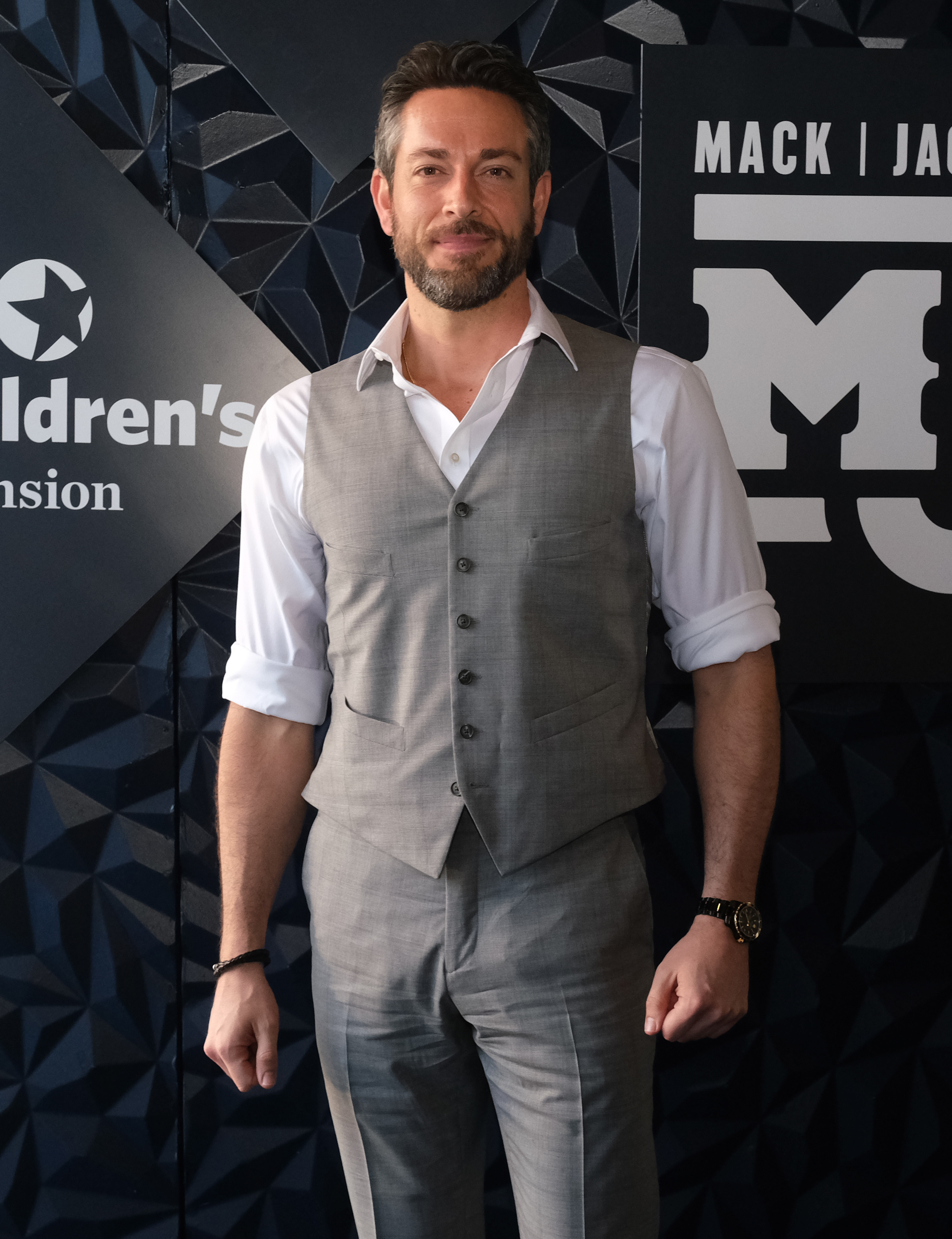closeup of him wearing a vest and slacks at an event