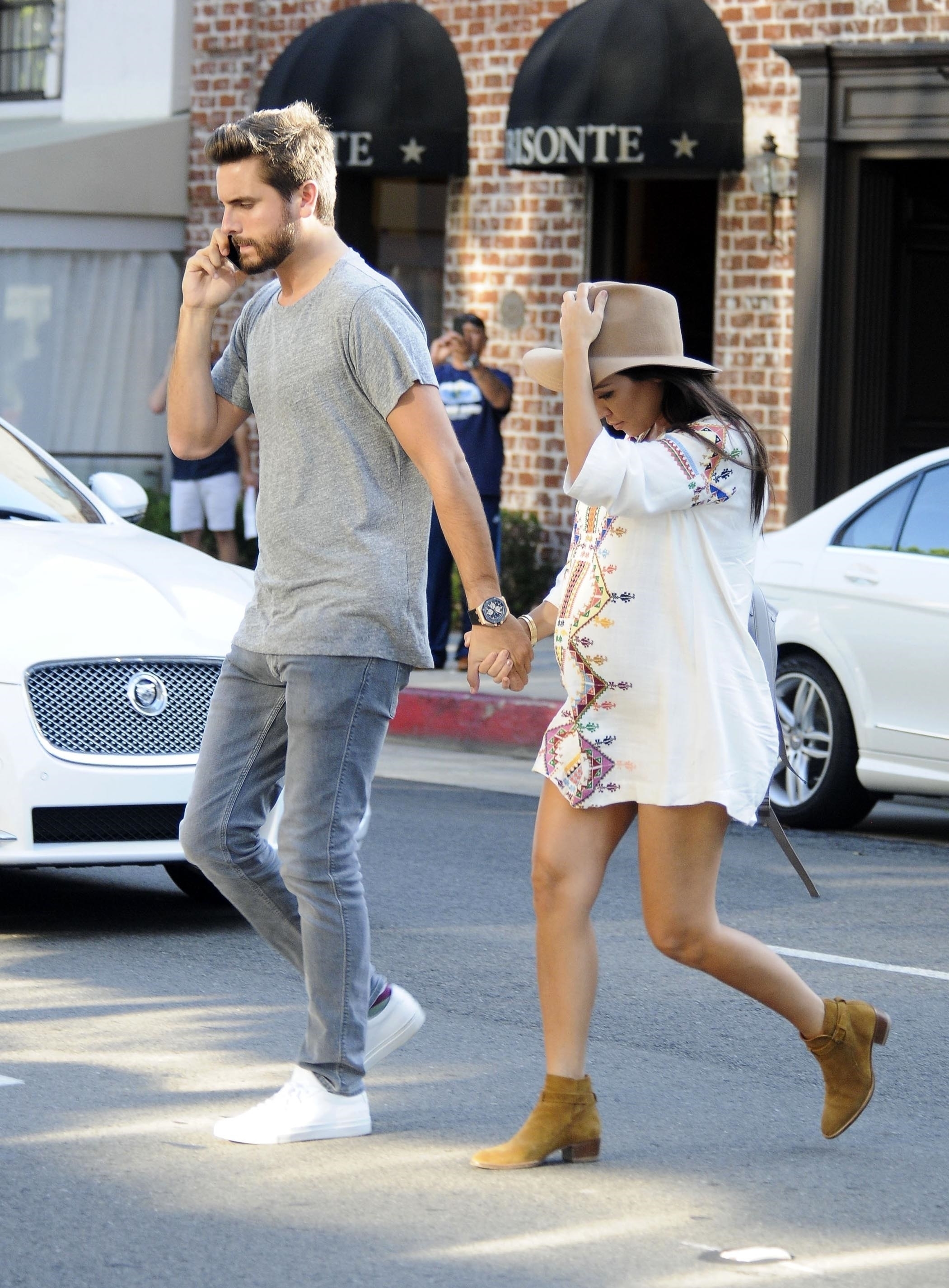 Scott Disick and a pregnant Kourtney Kardashian crossing the street as they hold hands