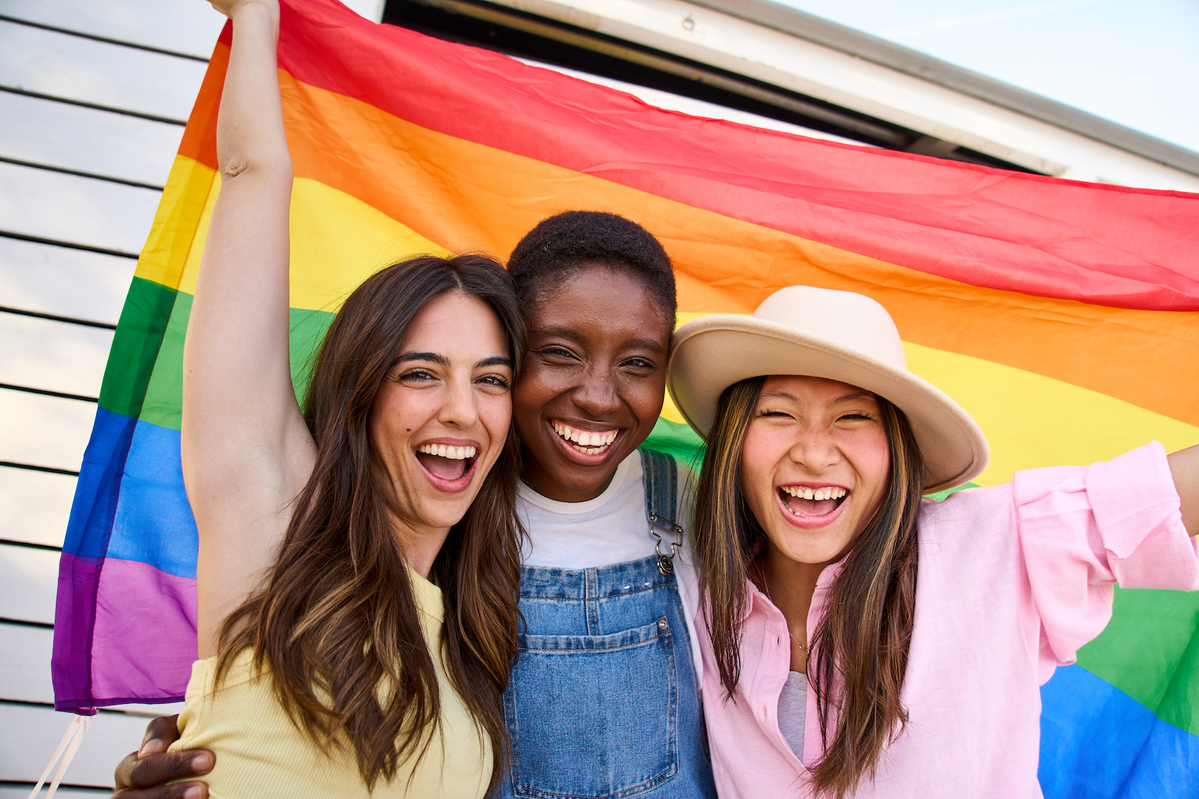 People smiling and rocking the LGBTQ flag