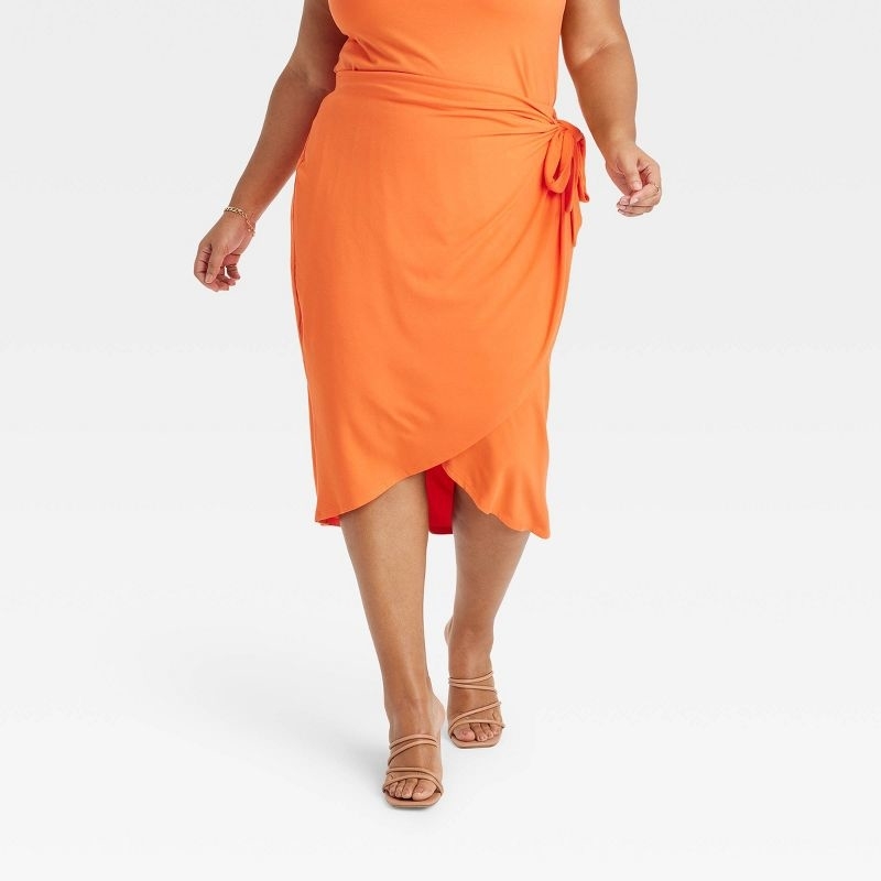 A model wearing an orange skirt with matching top