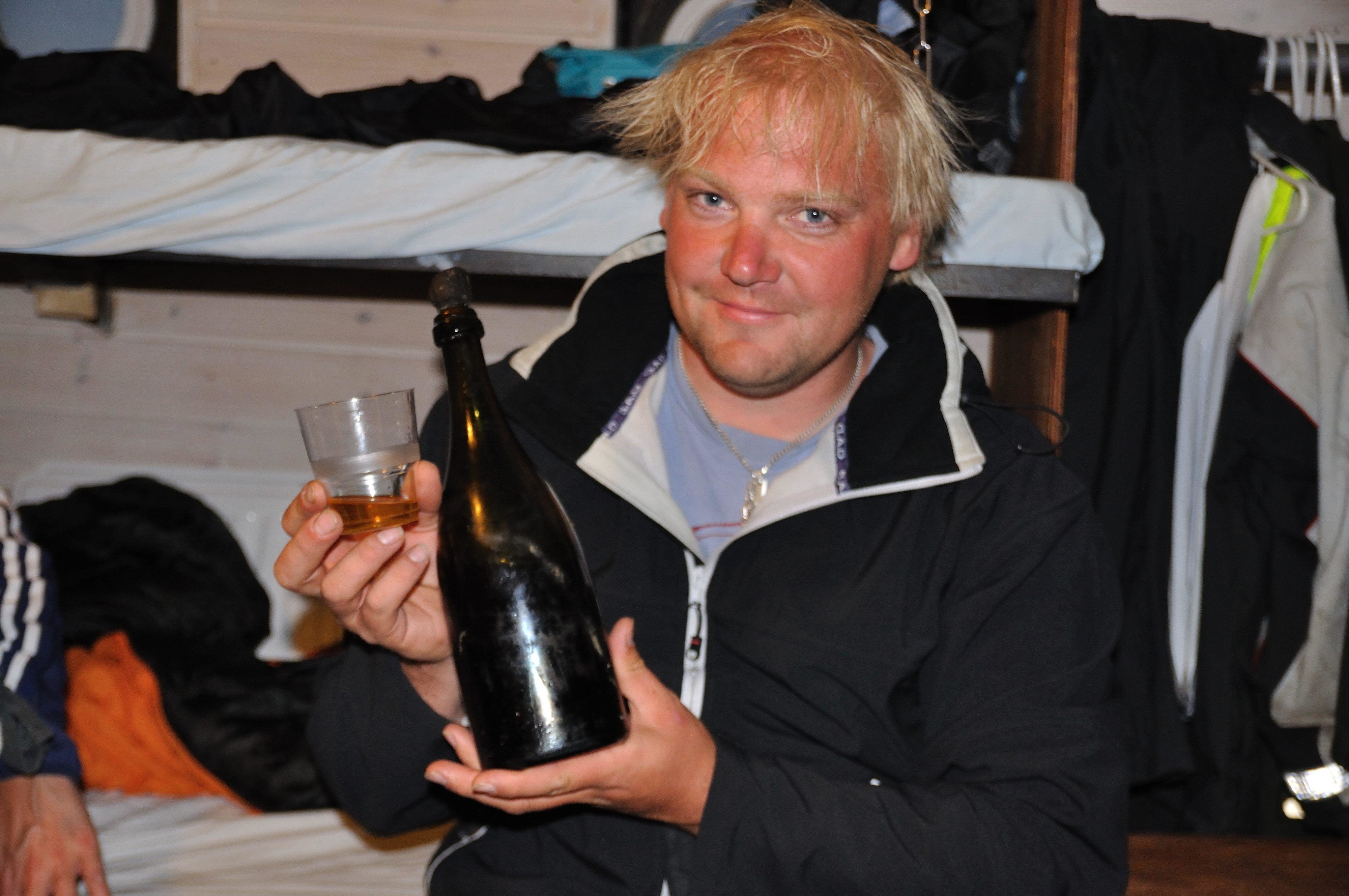 A smiling man holding a glass and a champagne bottle