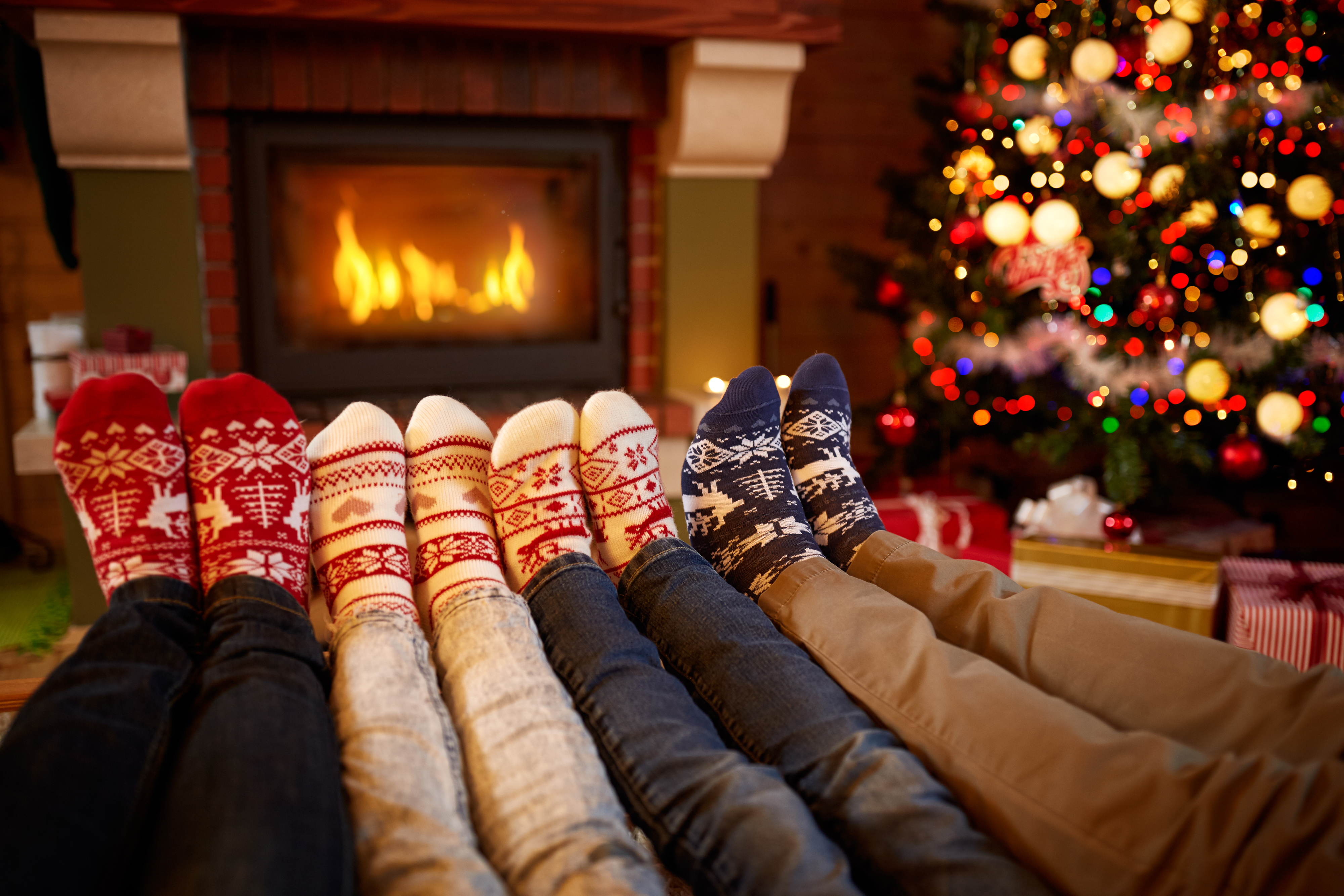 A variety of Christmas socks by a fireplace and decorated Christmas tree
