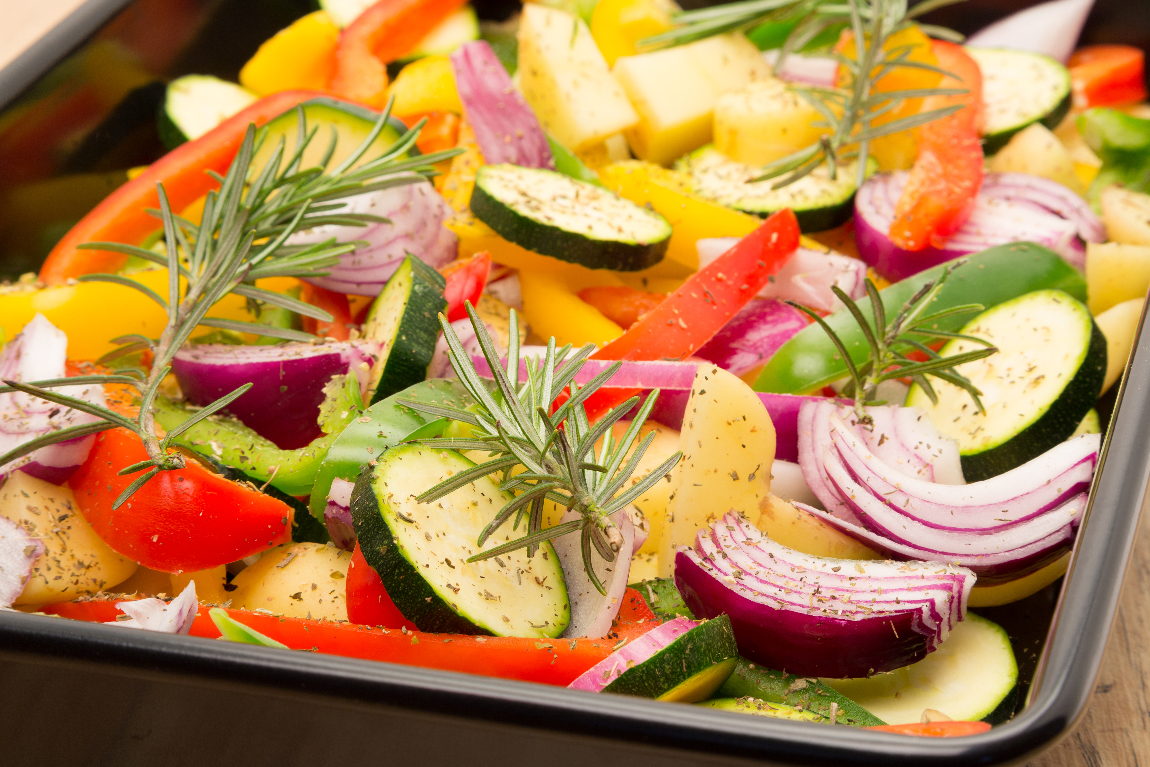 Variety of veggies getting roasted on a pan with seasoning