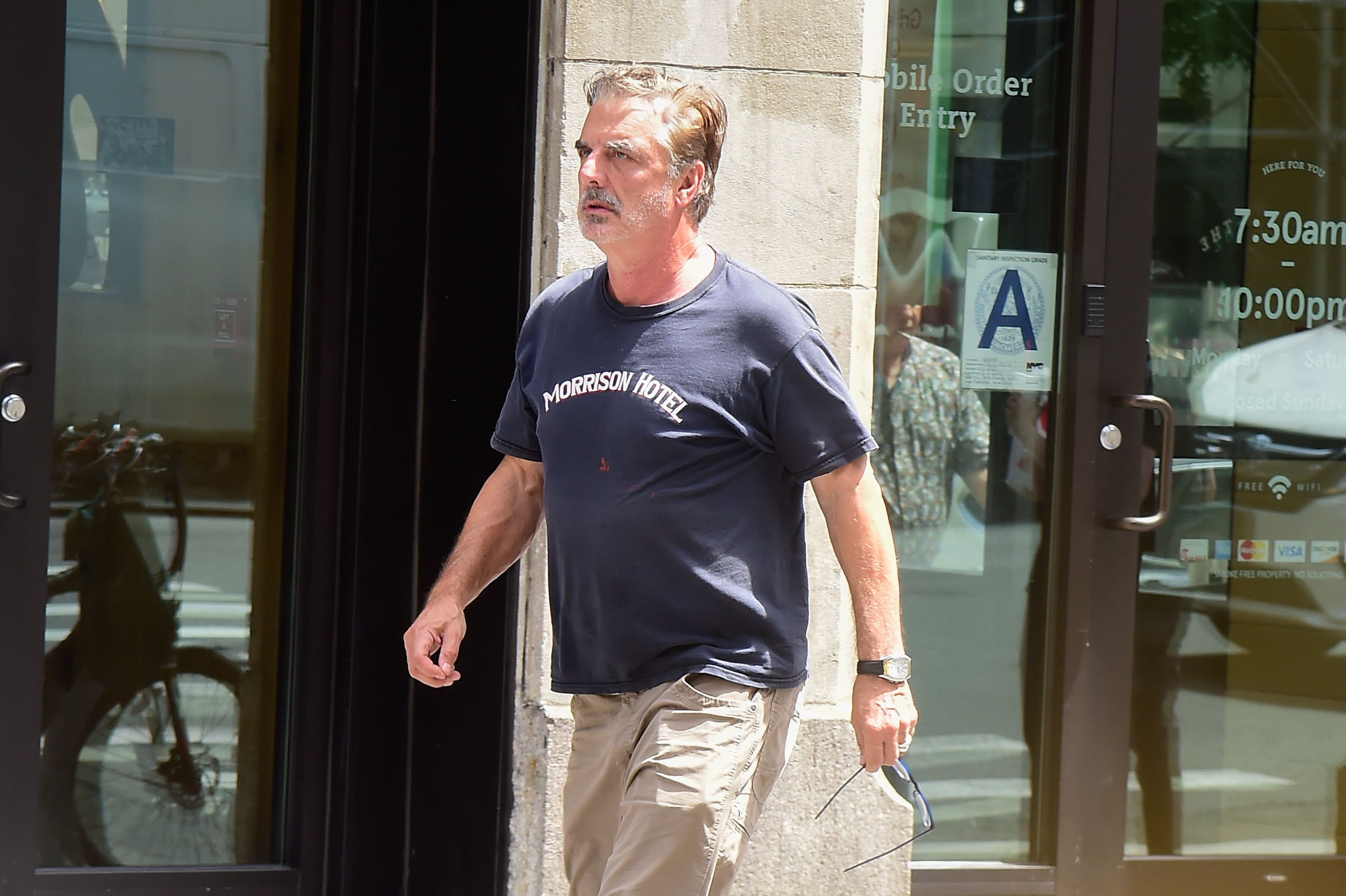 Closeup of Chris Noth walking while holding his glasses