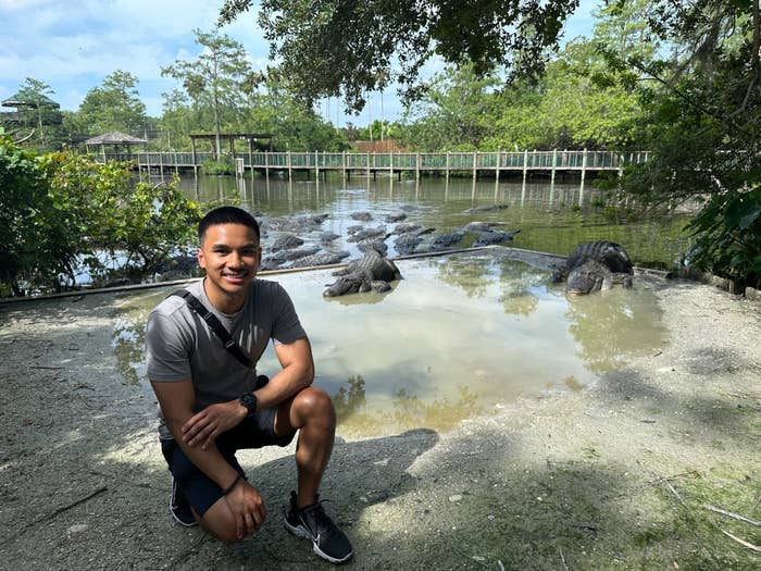 Godfrey crouching in front of a pool of alligators.