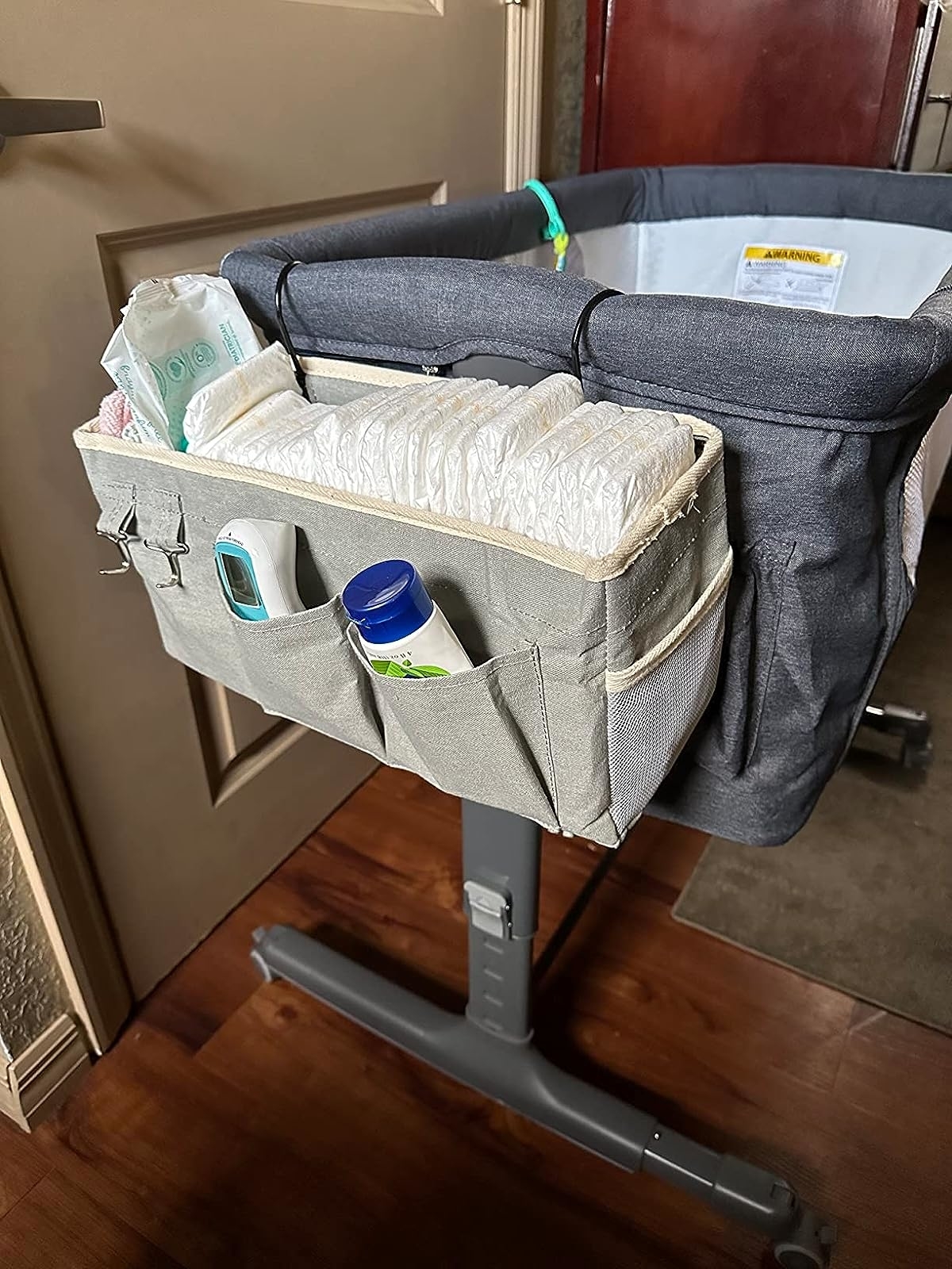 Reviewer image of the caddy hanging on a bassinet, filled with baby essentials