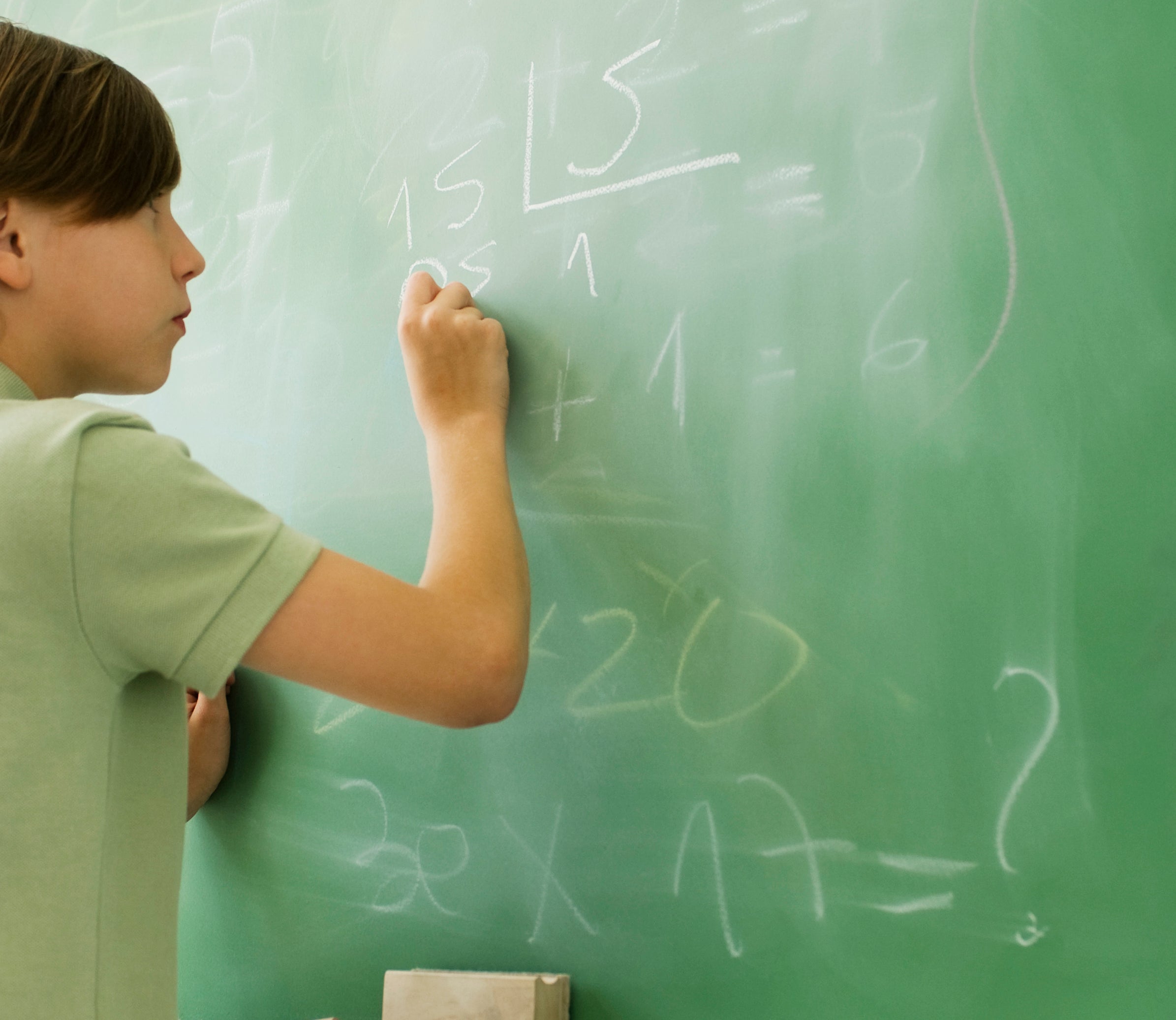 A student solving a math problem on the chalkboard