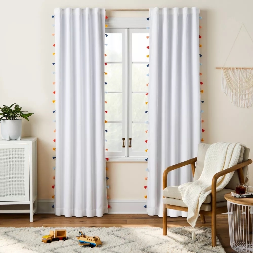 White curtain panels with colorful tassels hanging in a kids&#x27; bedroom