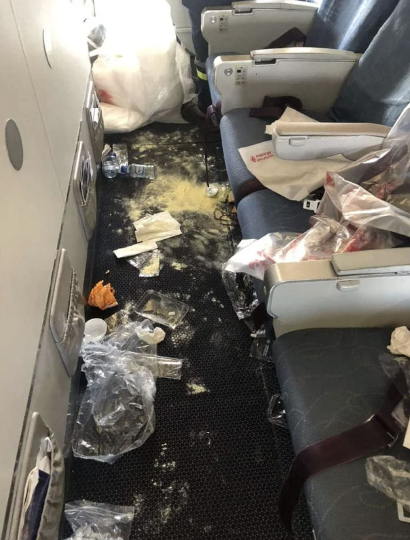 floor of the plane seats littered with food and plastic