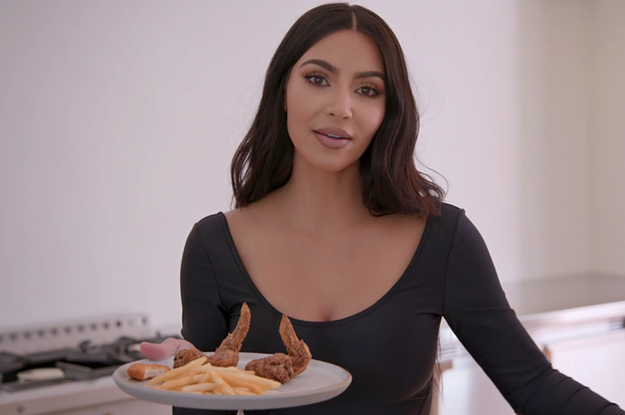 Km Kardashian holding a plate with fries and fried chicken on it