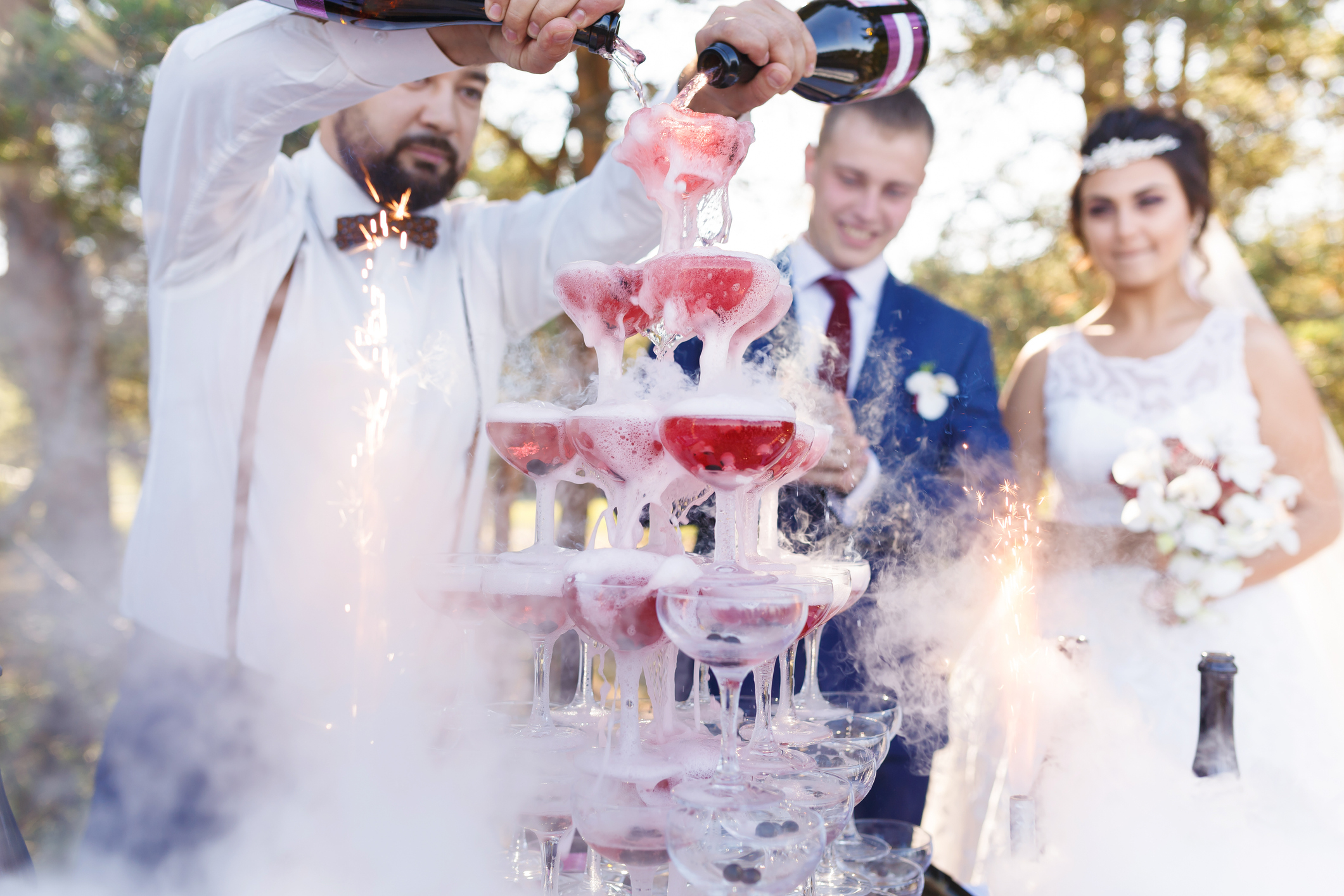 man making a champagne tower in front of the wedding couple