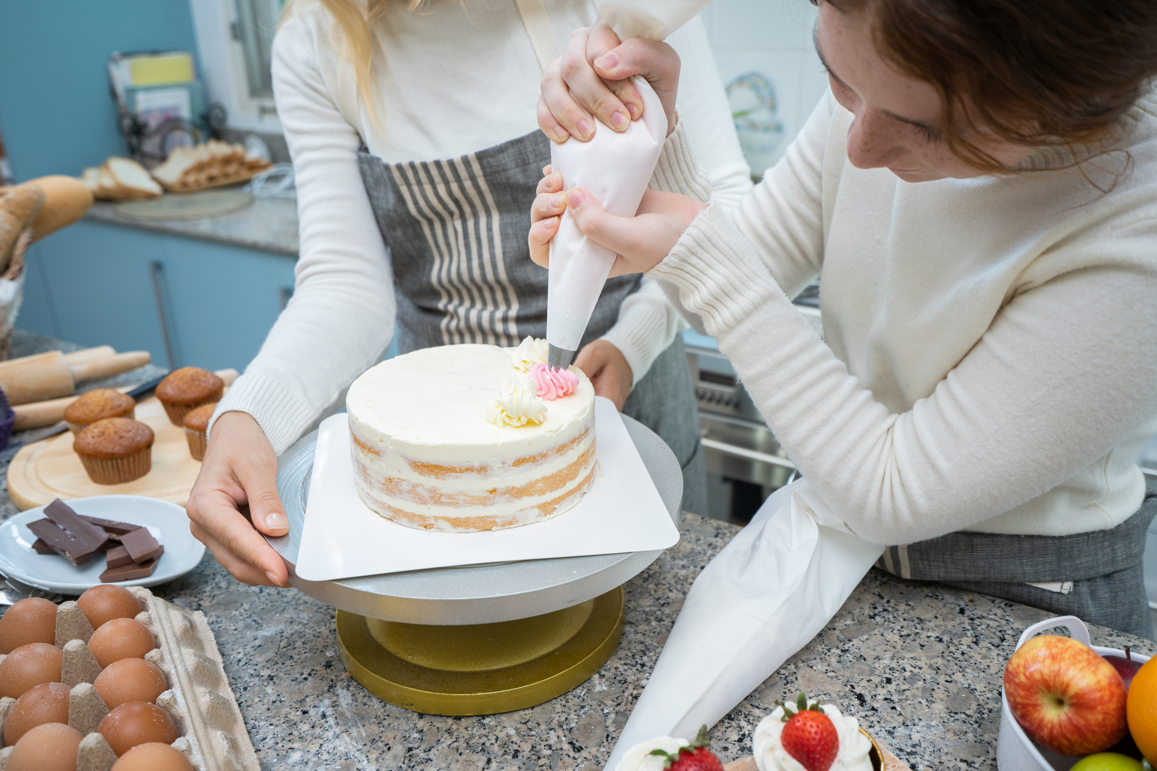 Two women decorating a cake