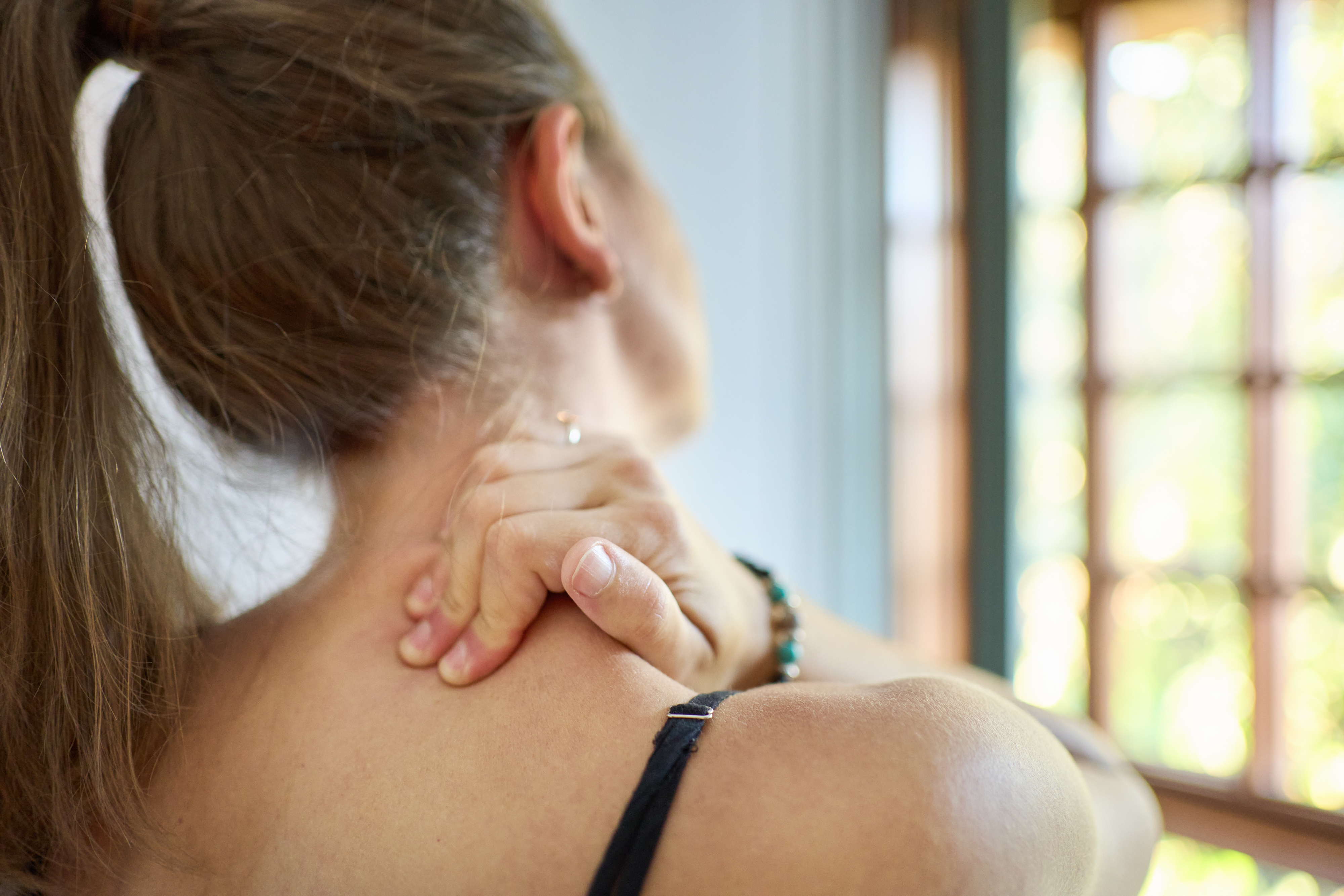 A woman grips her neck in pain