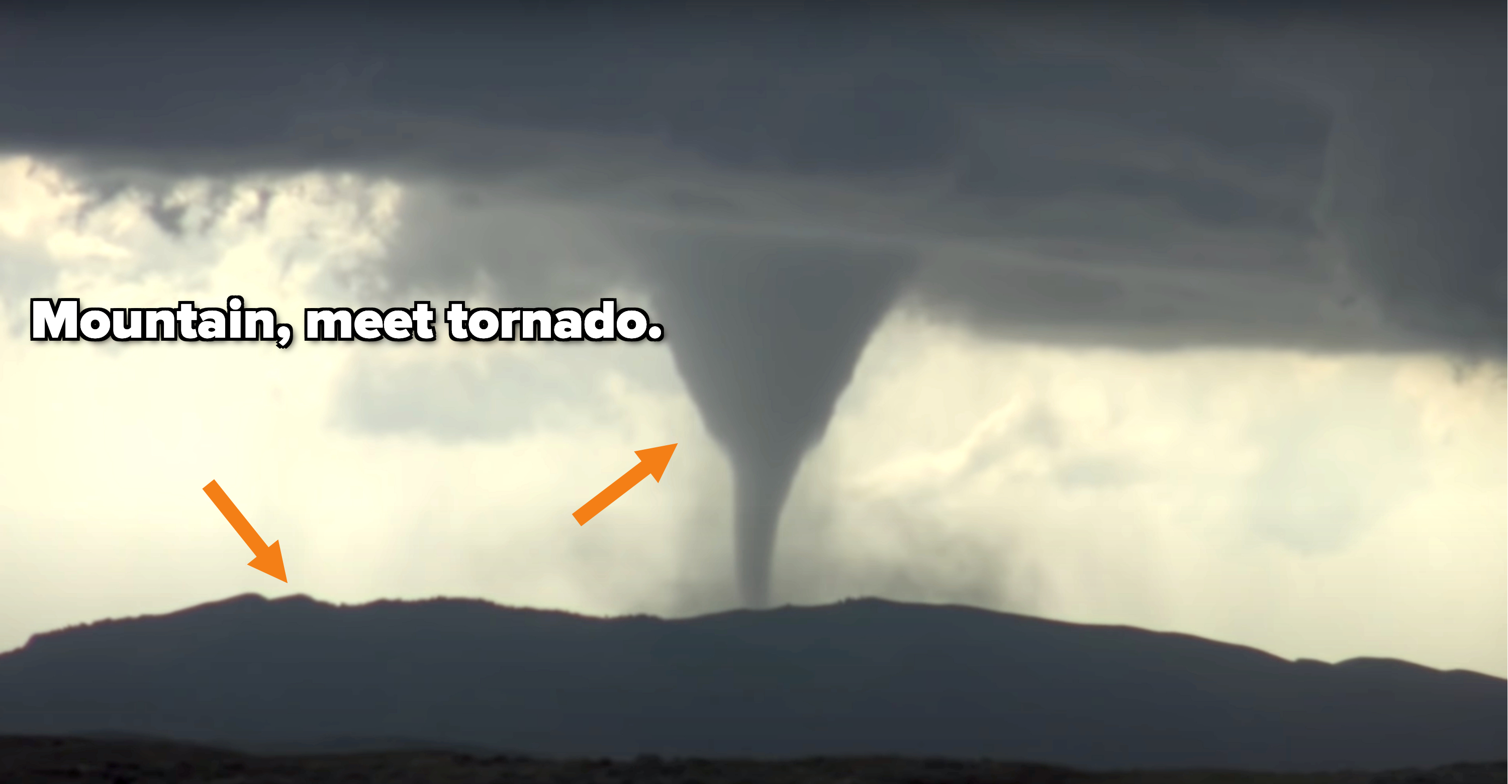 A very large tornado that has touched down on the very top of a mountain
