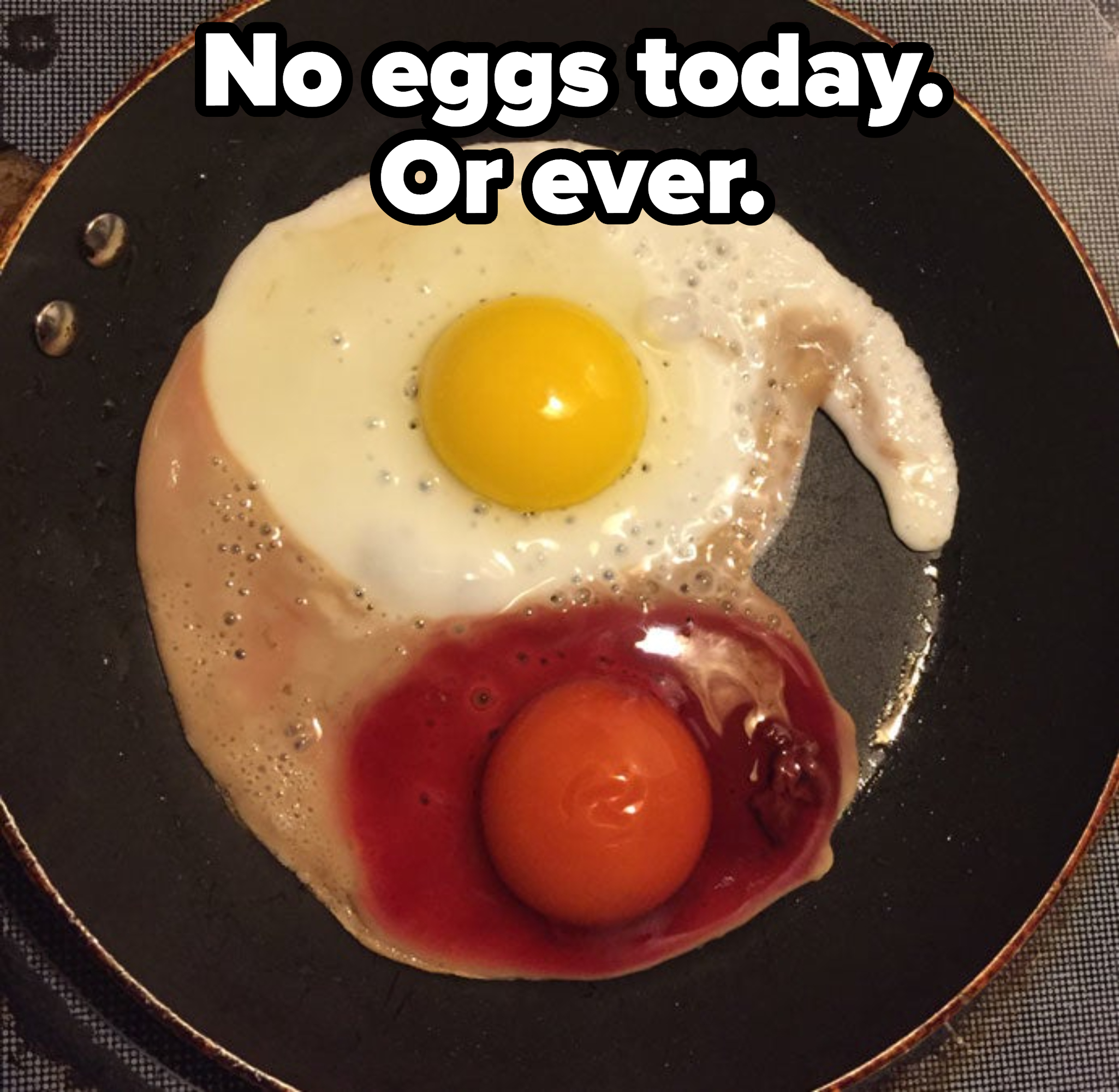 Two eggs frying in a pan — one of them is red