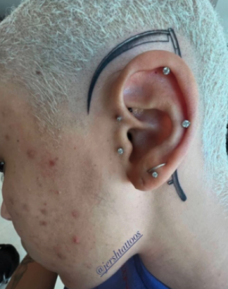 Close-up of the scythe tattoo behind Doja&#x27;s ear