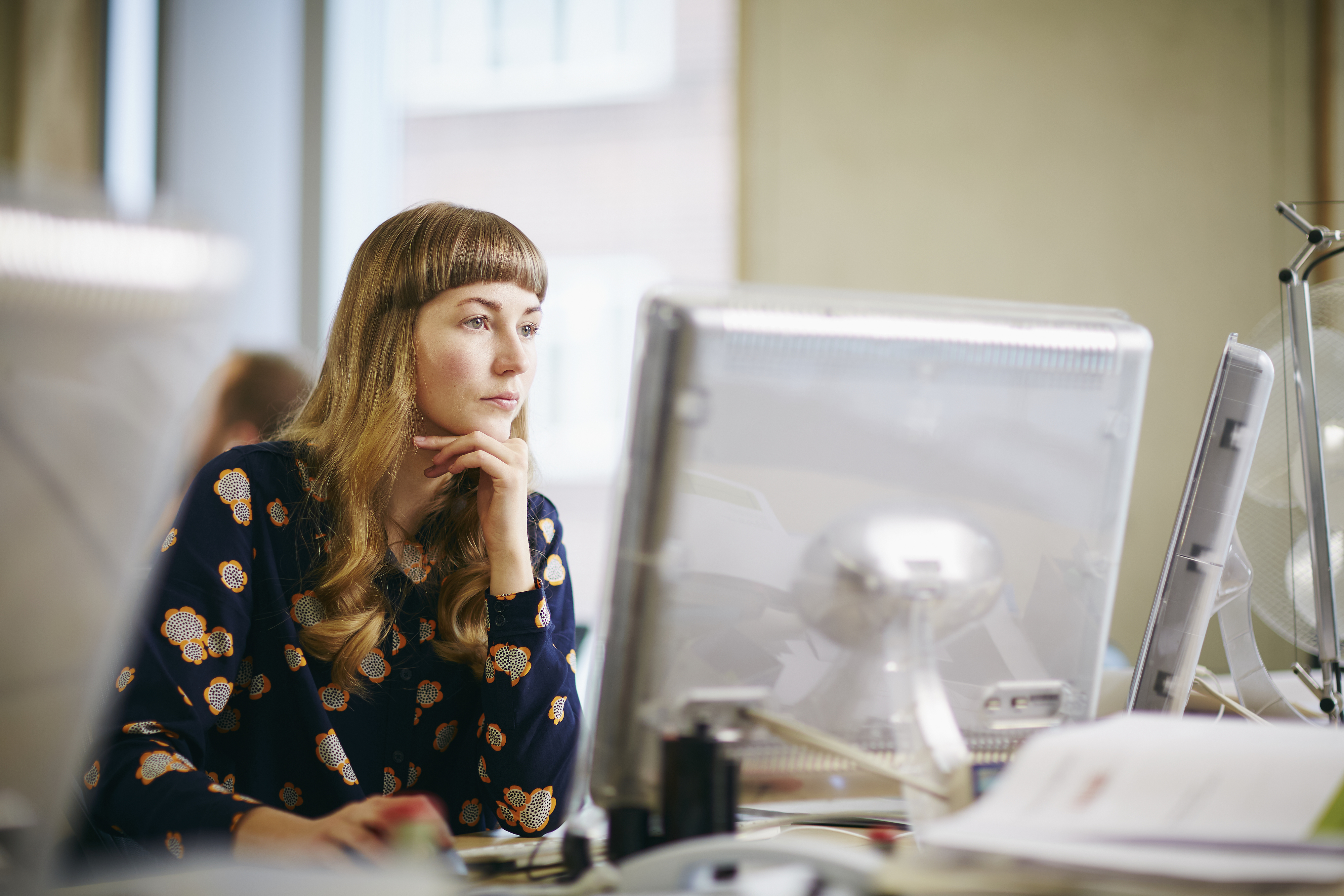 woman sitting at her desk wearing a long sleeved blouse