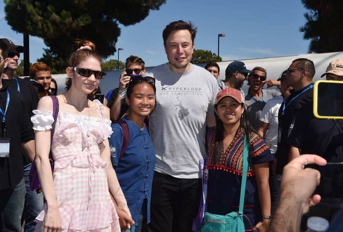 Grimes and Elon Musk posing for photos with people at an event