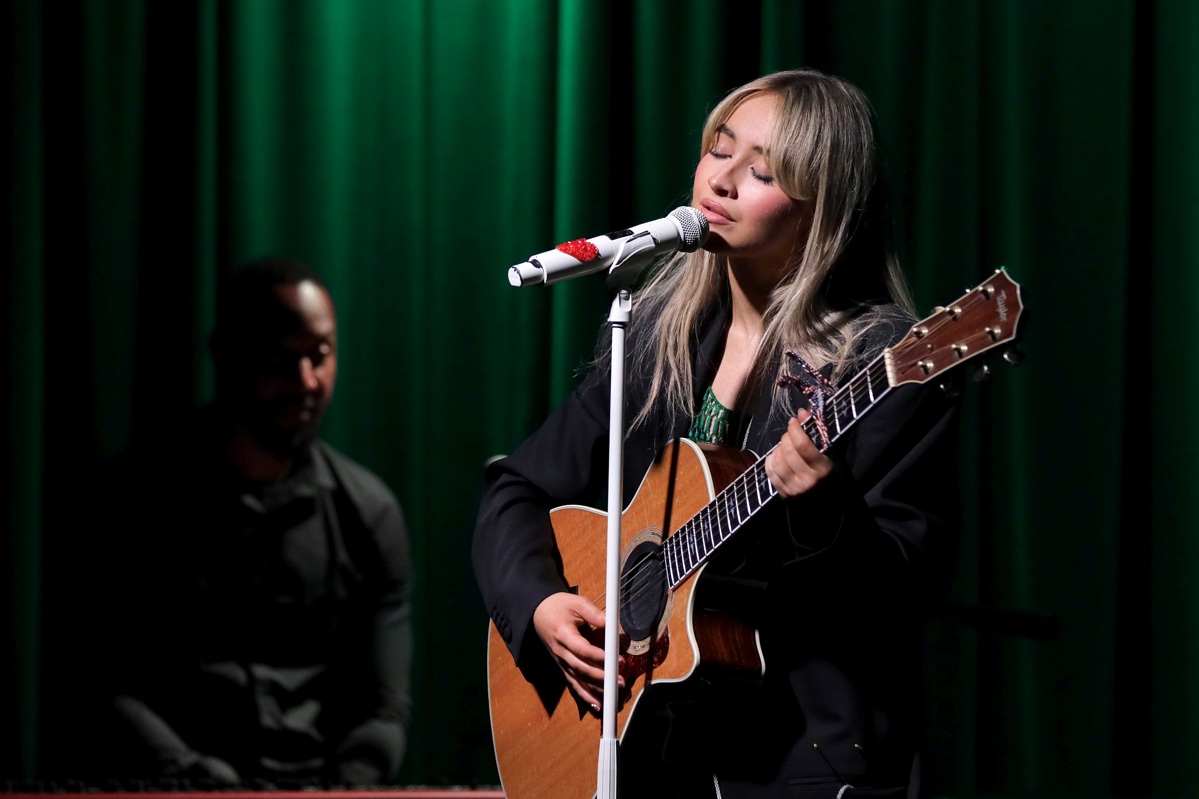 Sabrina Carpenter singing and playing the guitar onstage