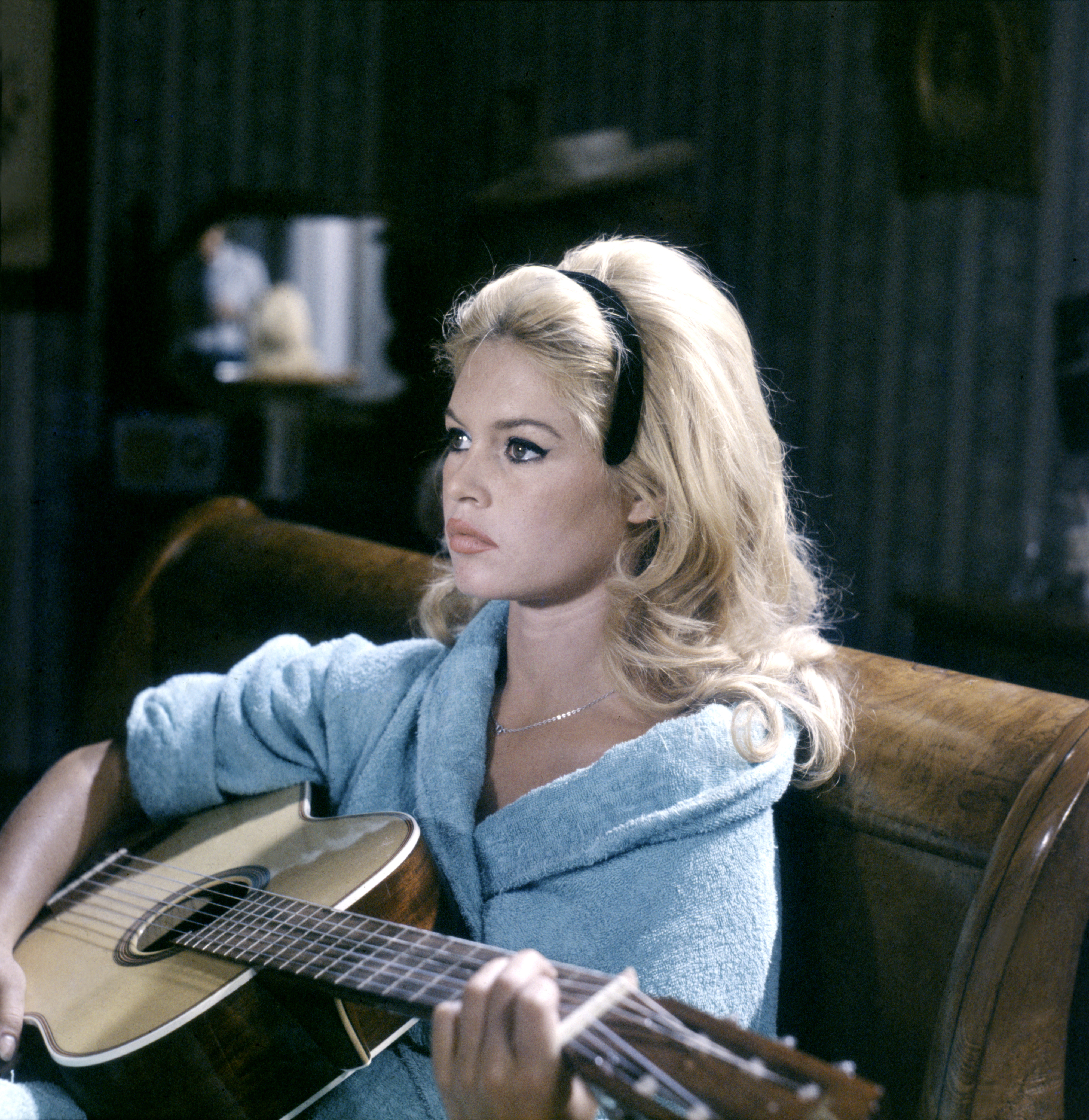 Brigitte Bardot seated and playing guitar