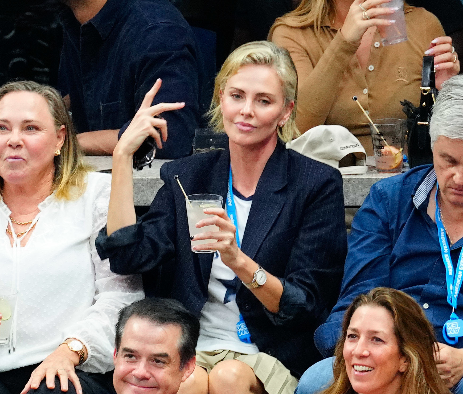 Charlize Theron holding a drink and holding up a peace sign