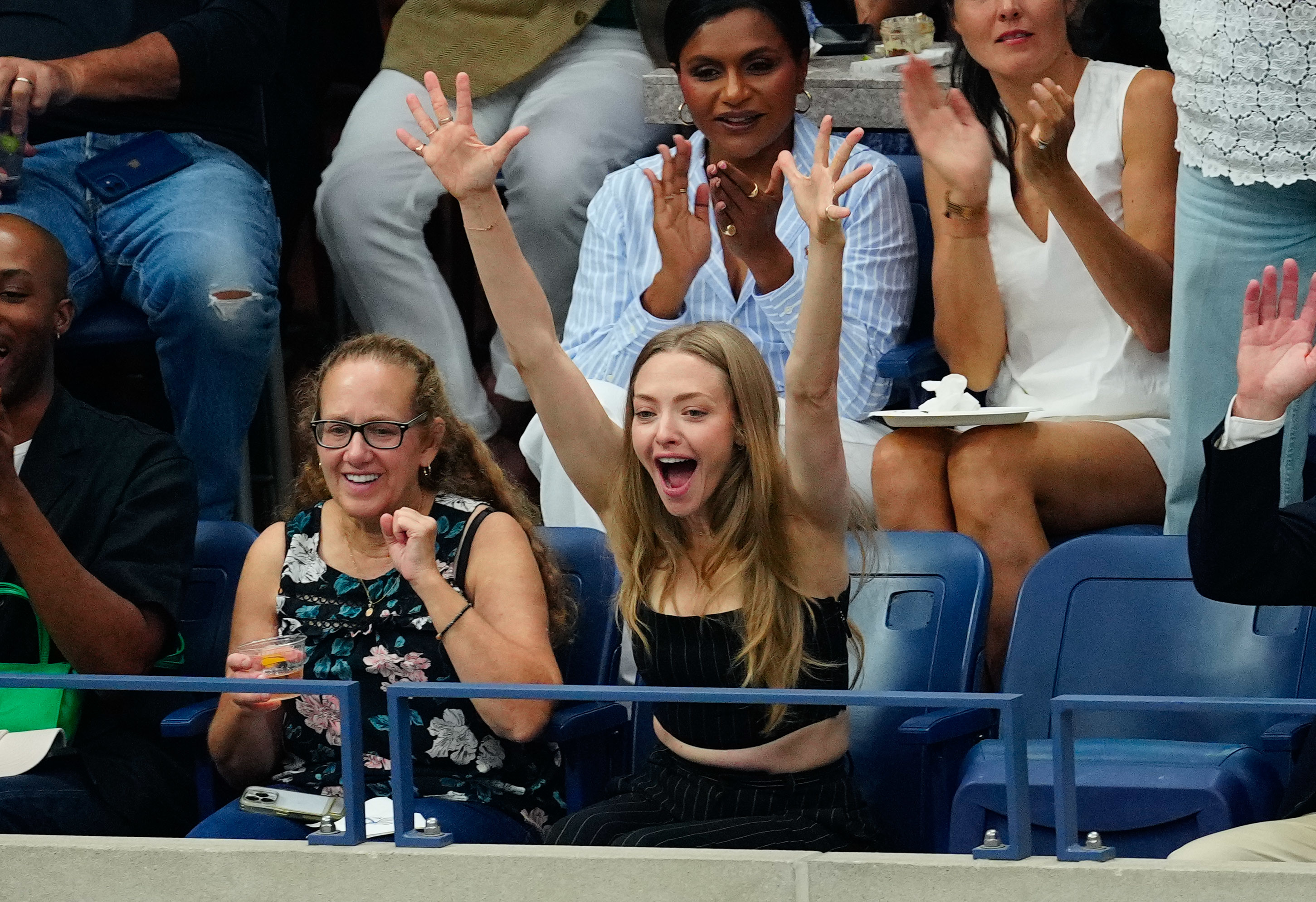 Amanda Seyfried cheering with her arms raised in the air