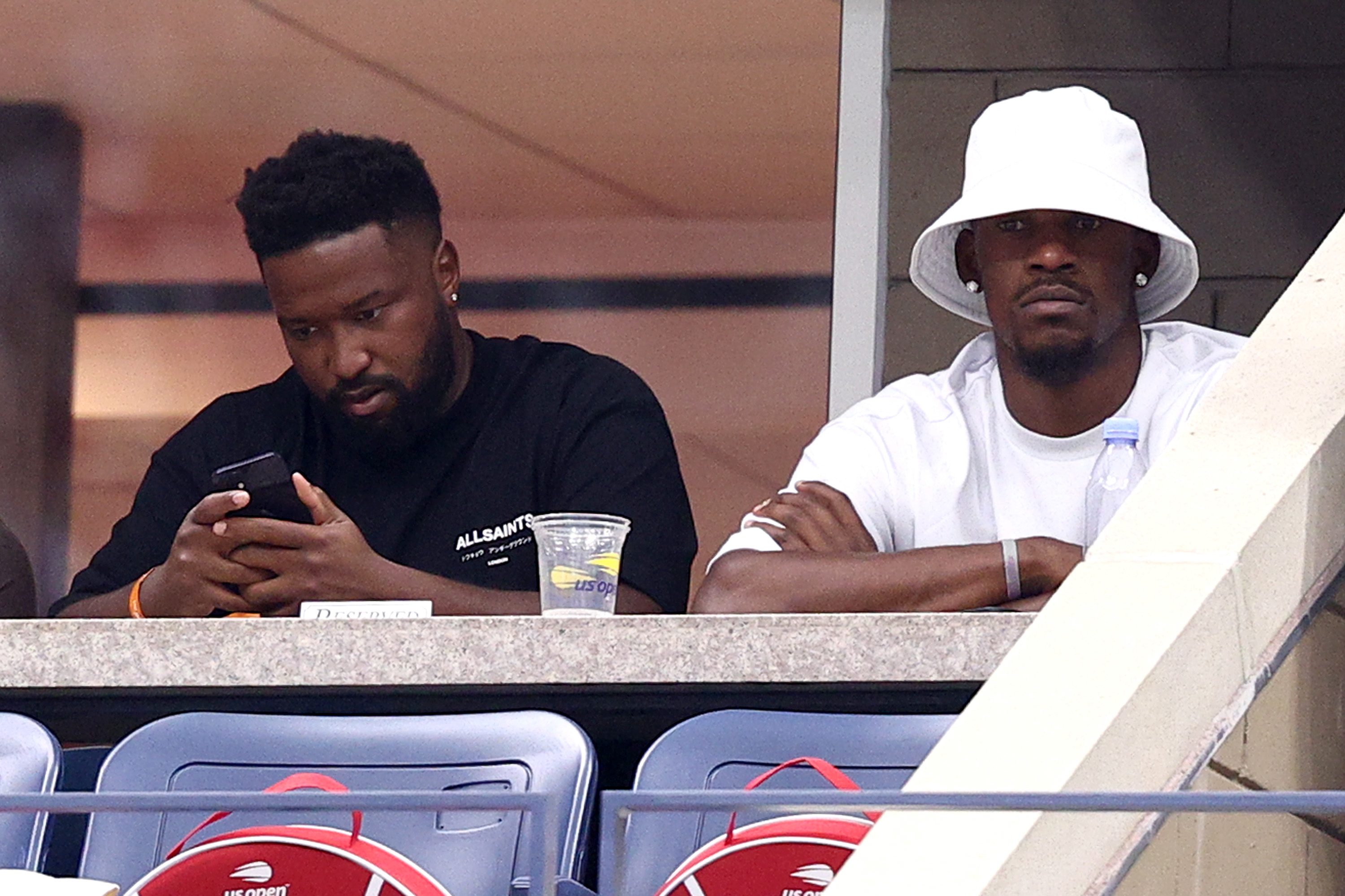 Jimmy Butler wearing a bucket hat as he sits with a friend