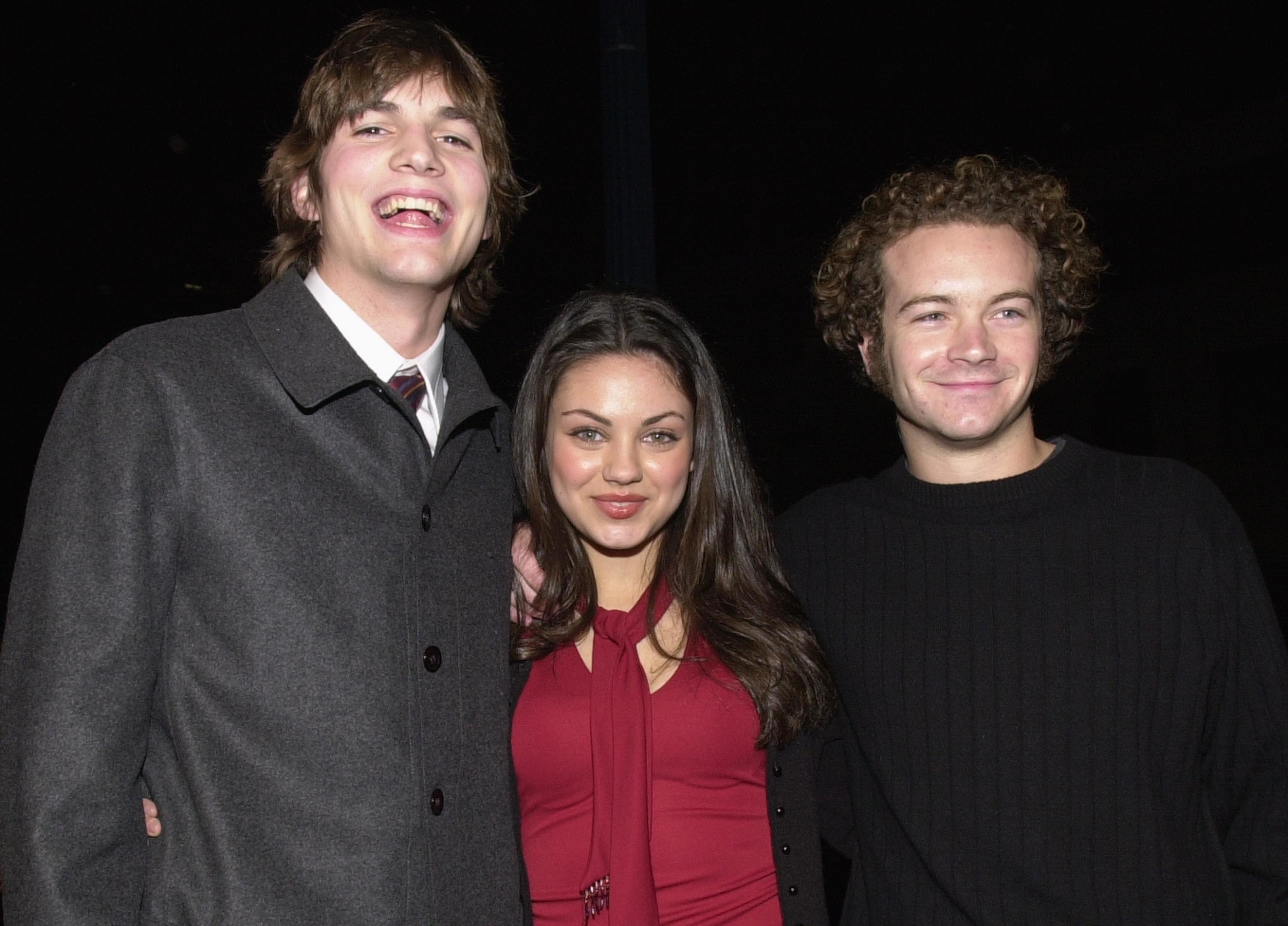 Close-up of Ashton, Mila, and Danny smiling and standing together