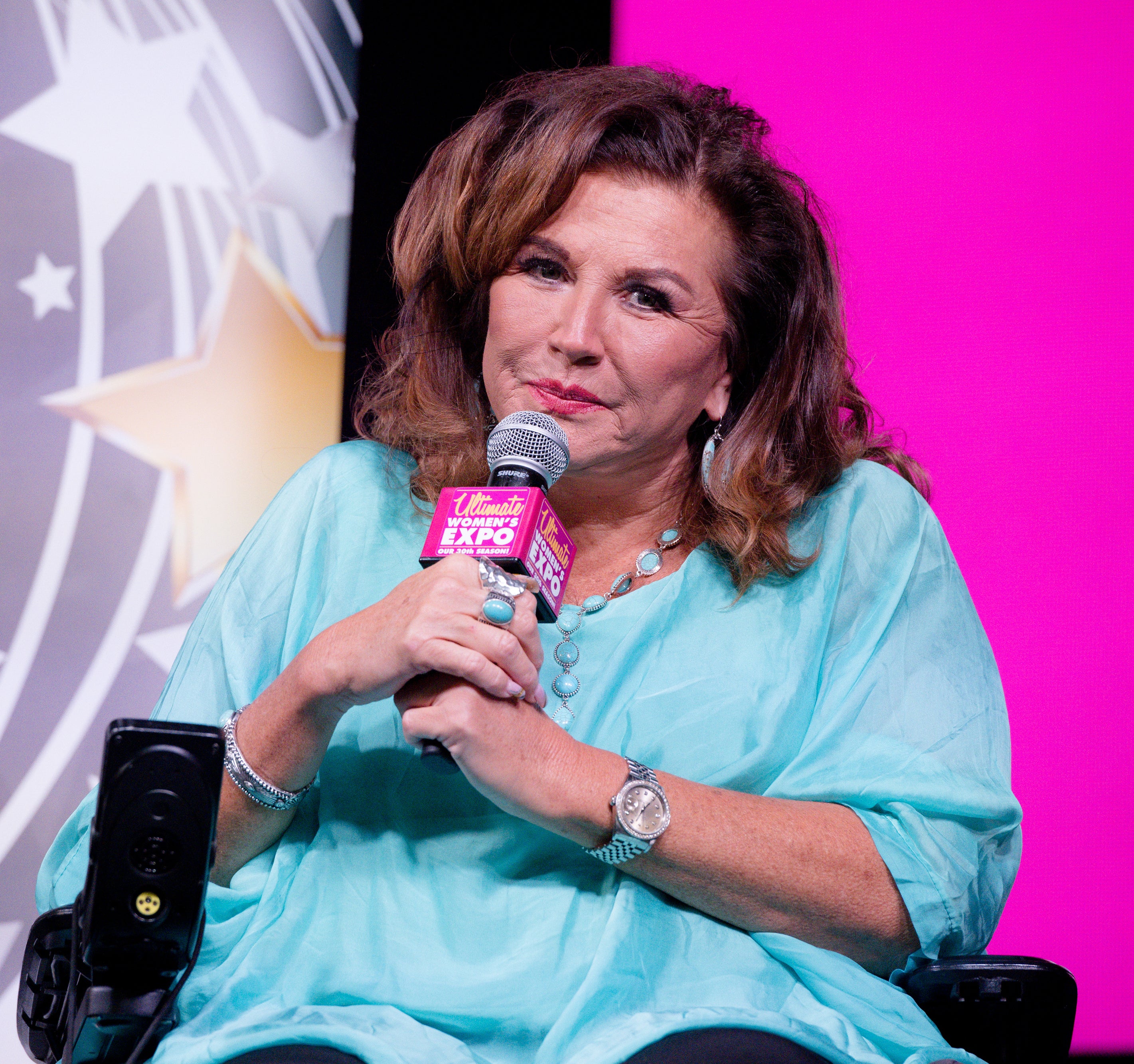 Abby seated and speaking into a microphone