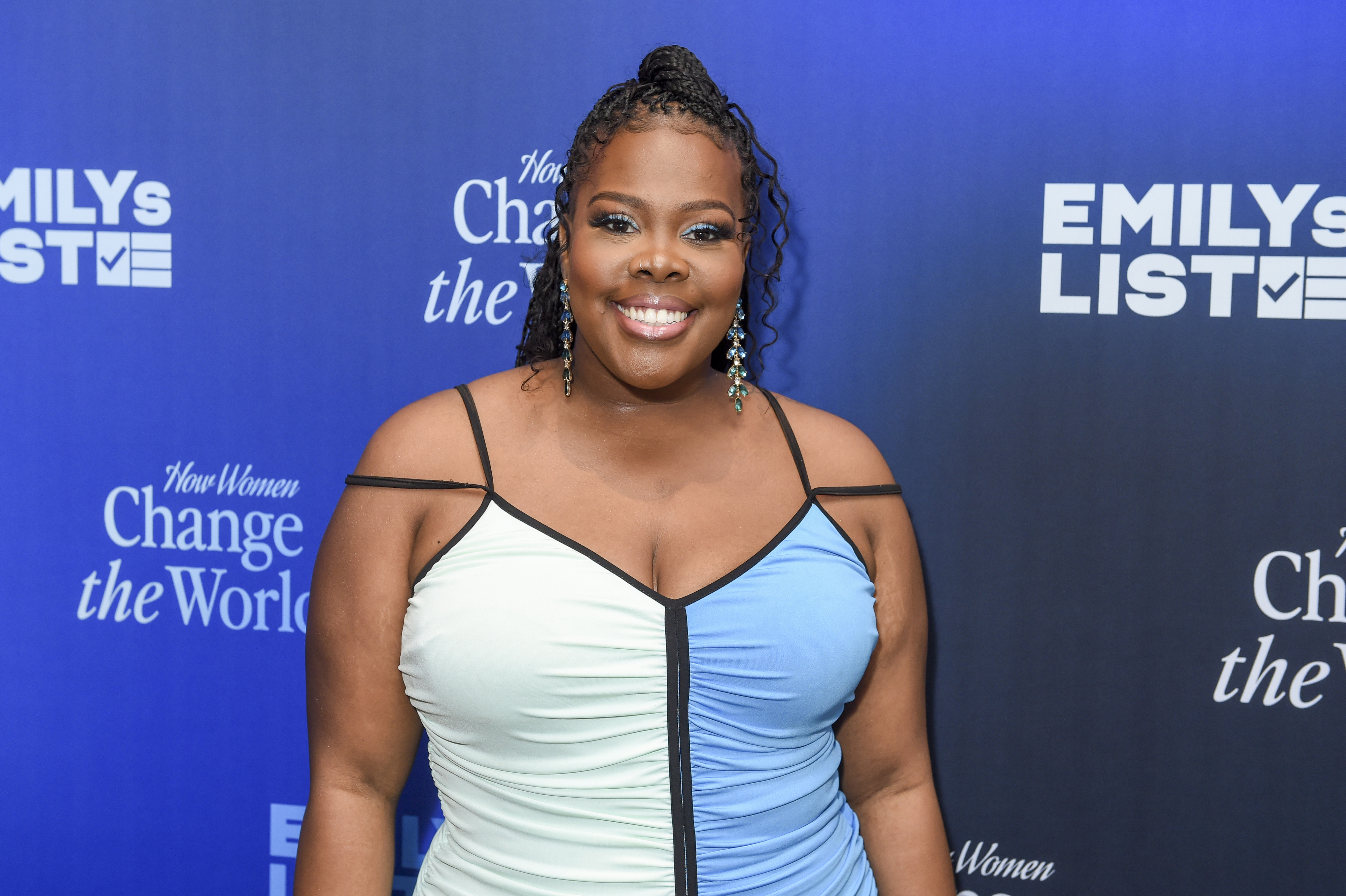 A closeup of Amber Riley smiling on the red carpet of a media event
