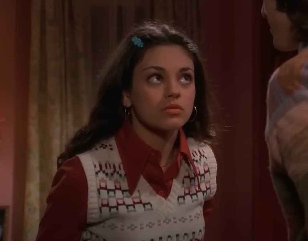 Screenshot of Mila from the show, wearing a shirt and vest