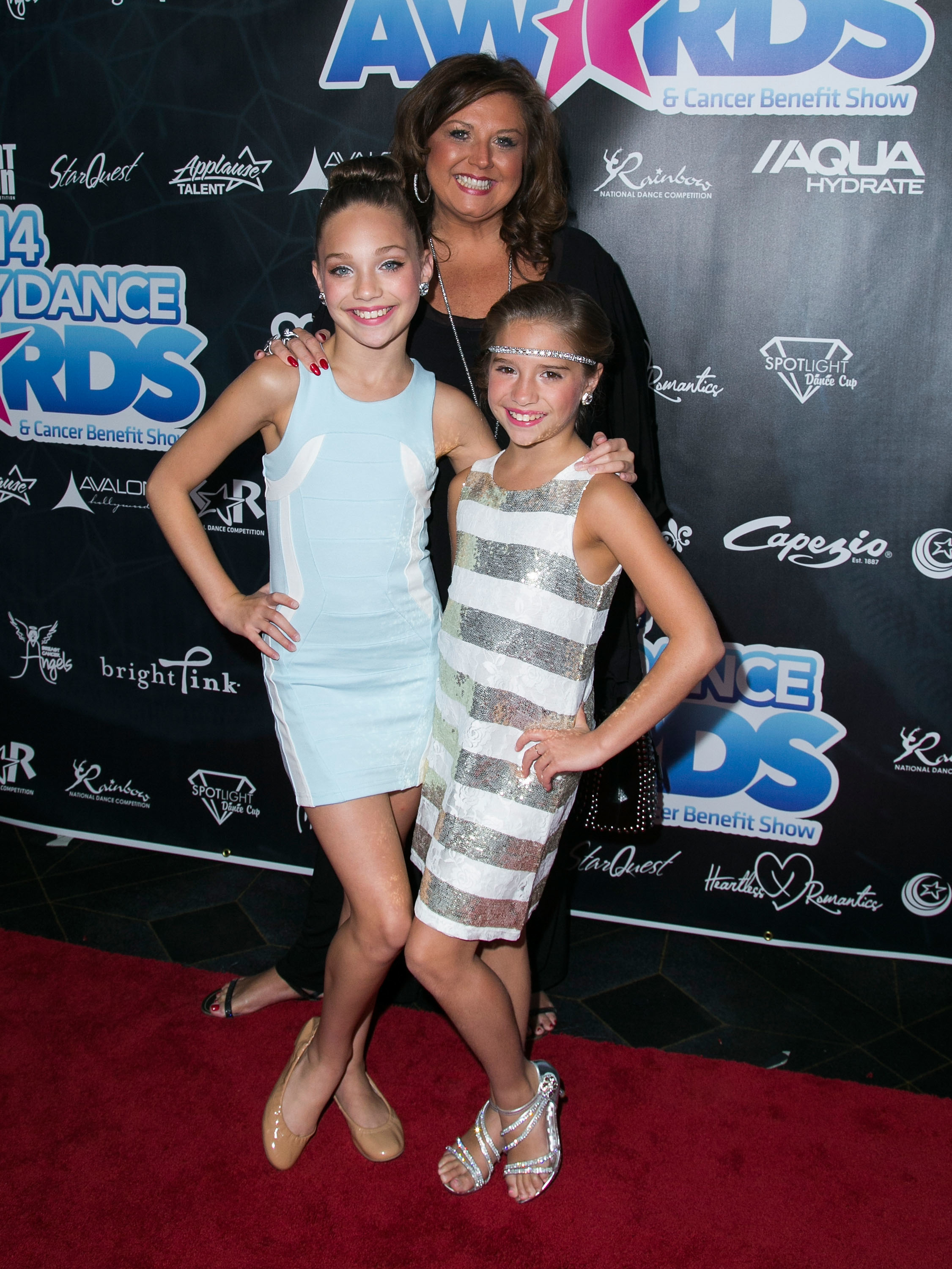 Maddie and Mackenzie smiling with Abby on the red carpet