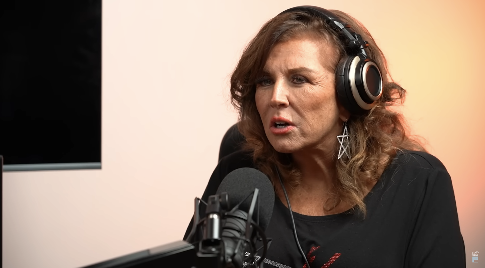 Abby seated and speaking into a microphone and wearing headphones