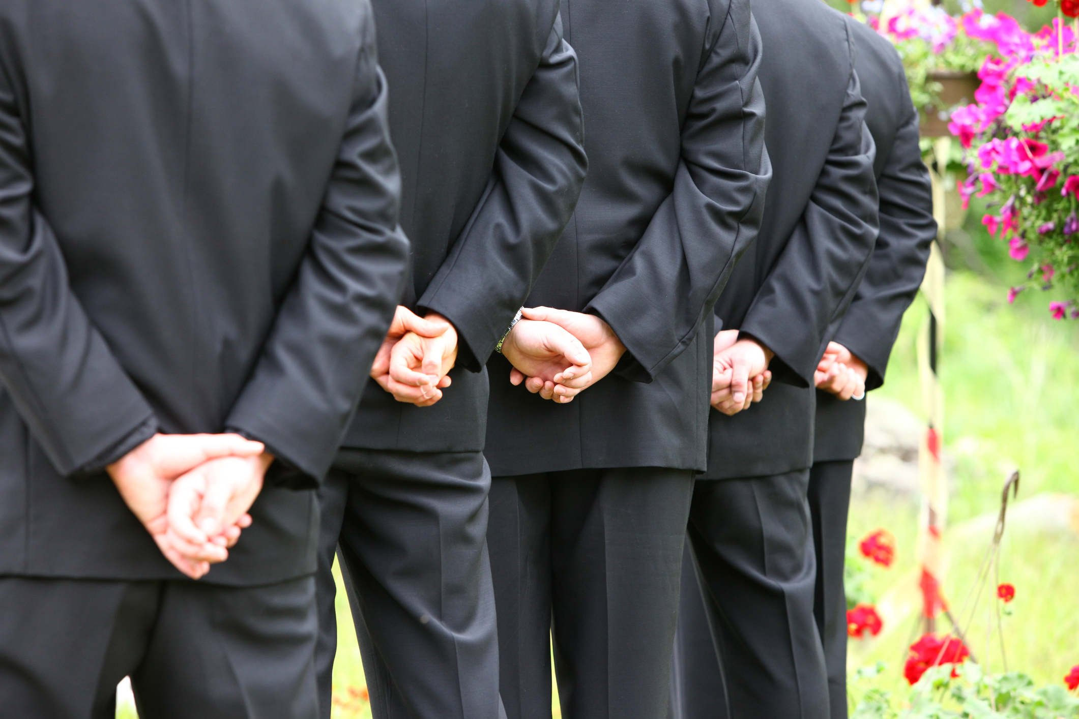 A group of groomsmen with their hands behind their backs