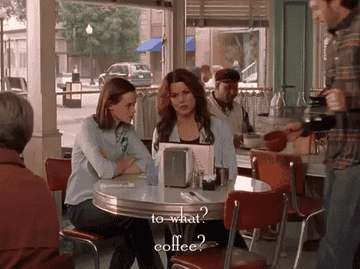 Man pours coffee for two women in a diner
